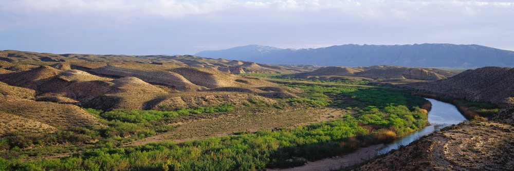 River flowing through desert valley with hills and mountains