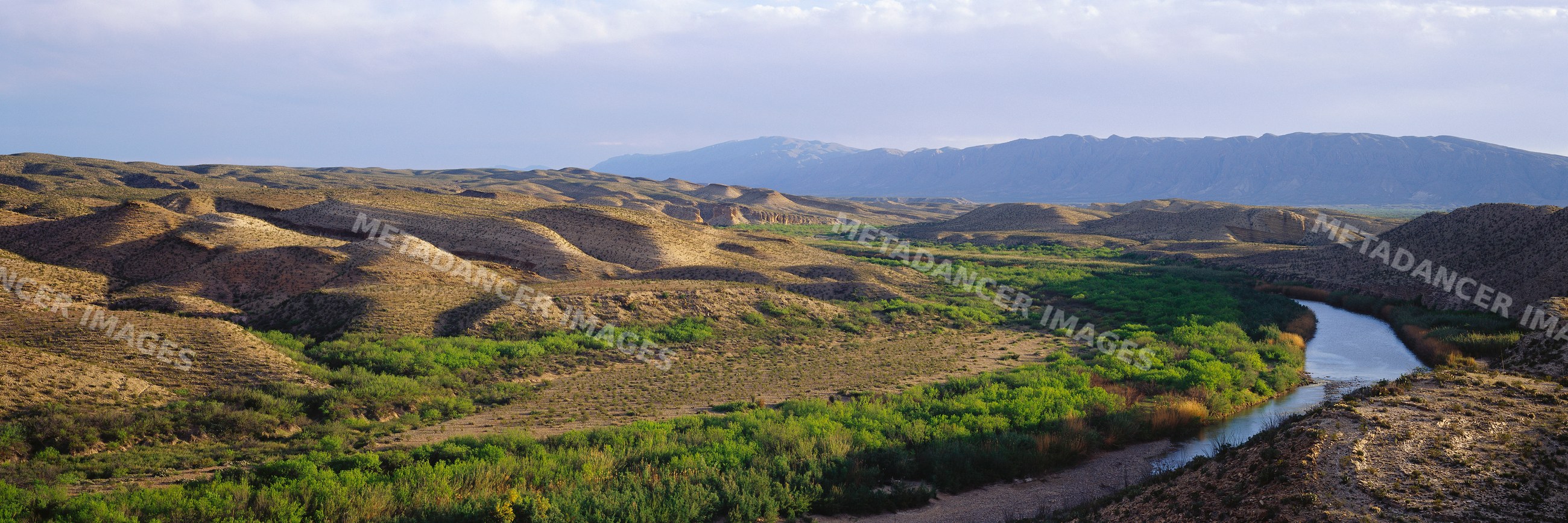 River flowing through desert valley with hills and mountains