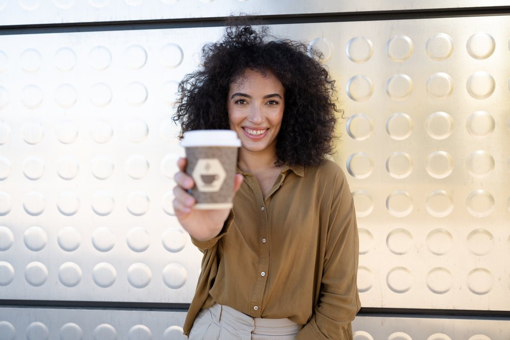 Smiling woman holding takeaway coffee cup outdoors in Madrid, Spain
