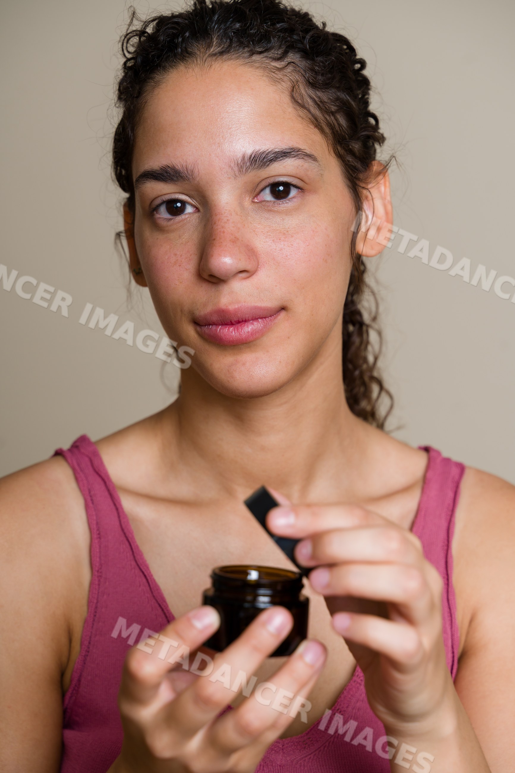 Hispanic woman holding jar of skin cream in beauty shoot in Spain