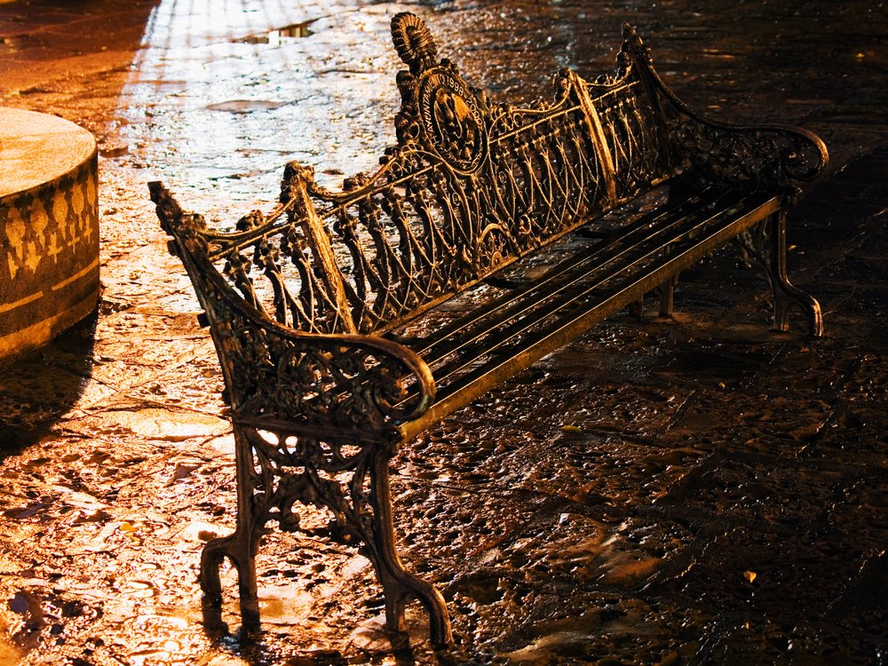 Metal park bench with ornate ironwork at night, mexico