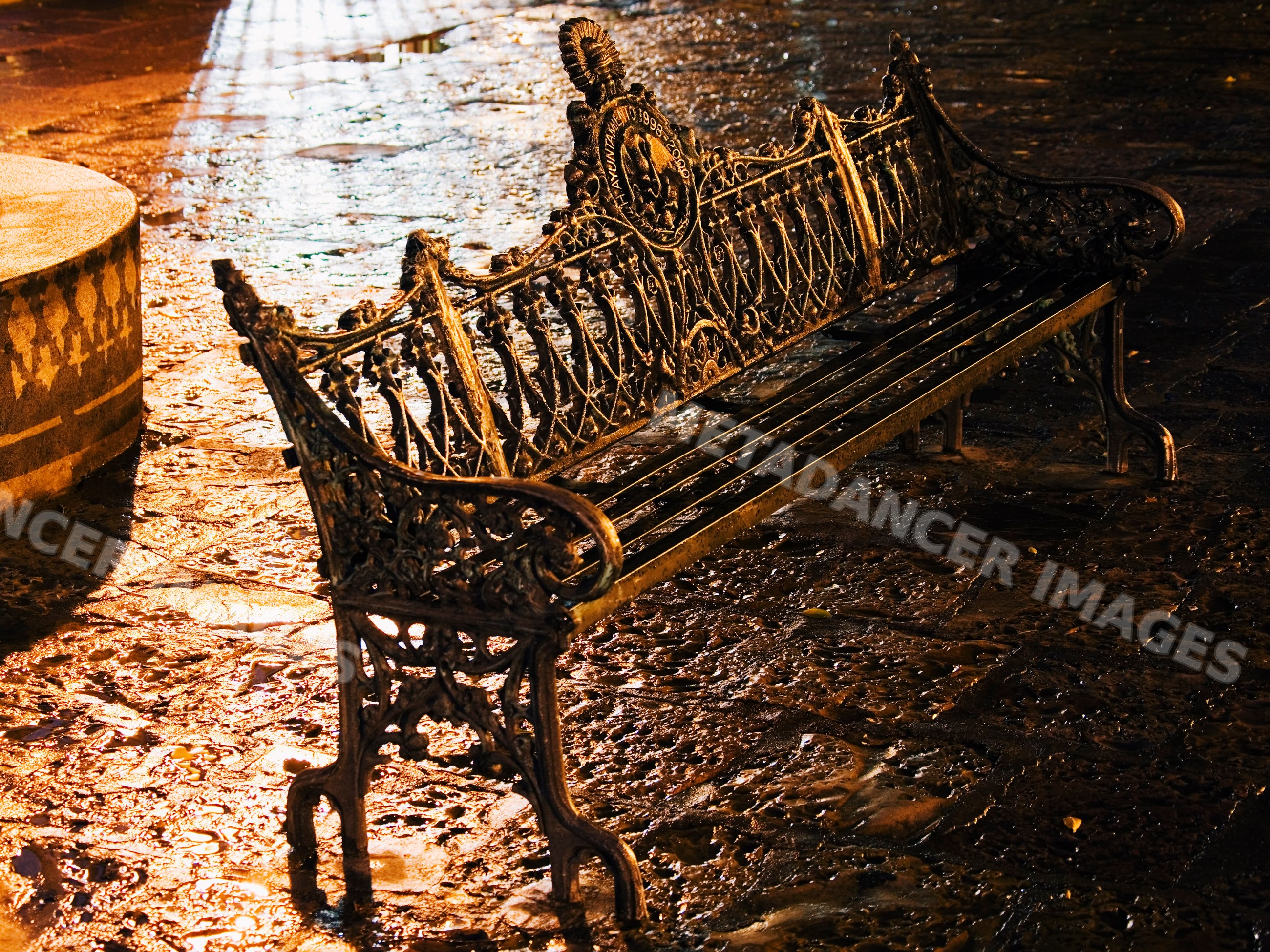 Metal park bench with ornate ironwork at night, mexico