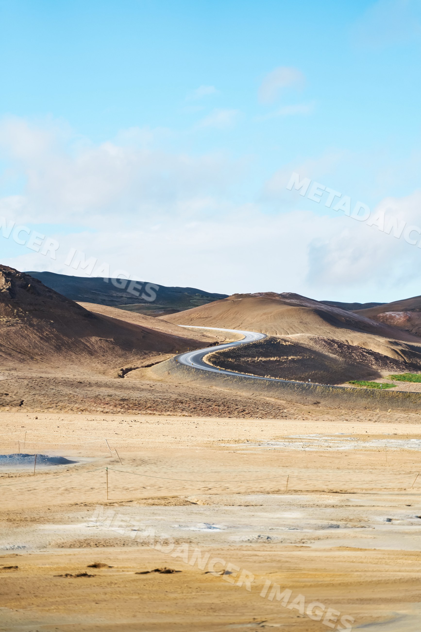 Winding road through barren brown hills in icelandic dry landscape