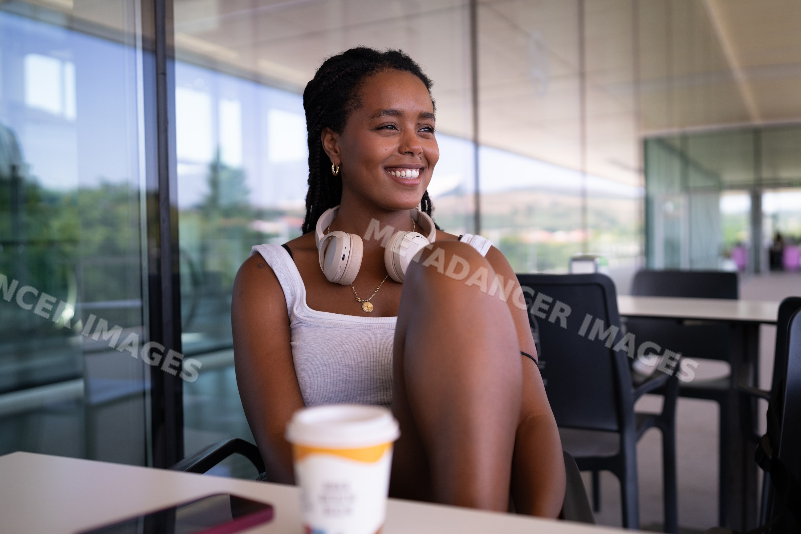 A African American woman wearing headphones enjoys coffee on a modern