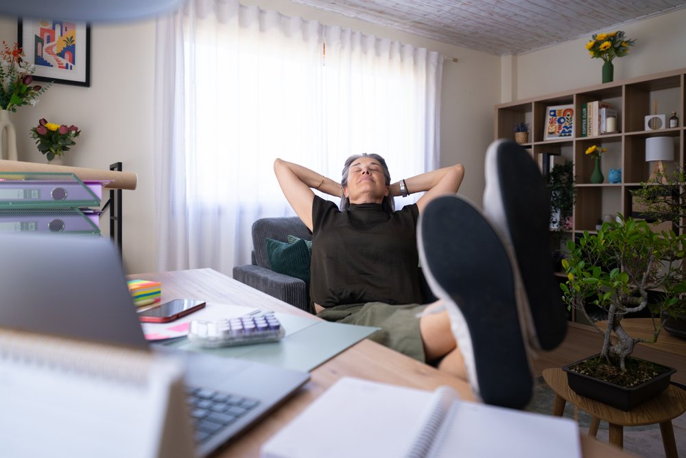 White woman relaxing with feet on desk in home office workspace
