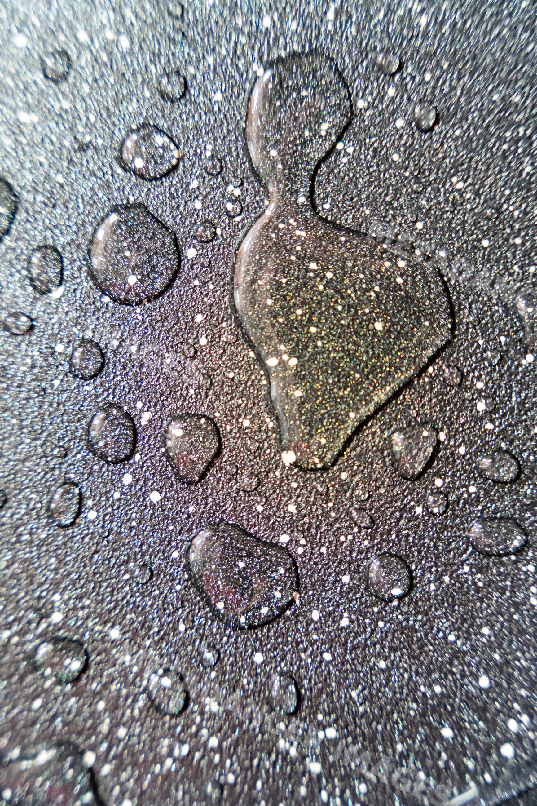 Water droplets creating abstract textured pattern on wet surface