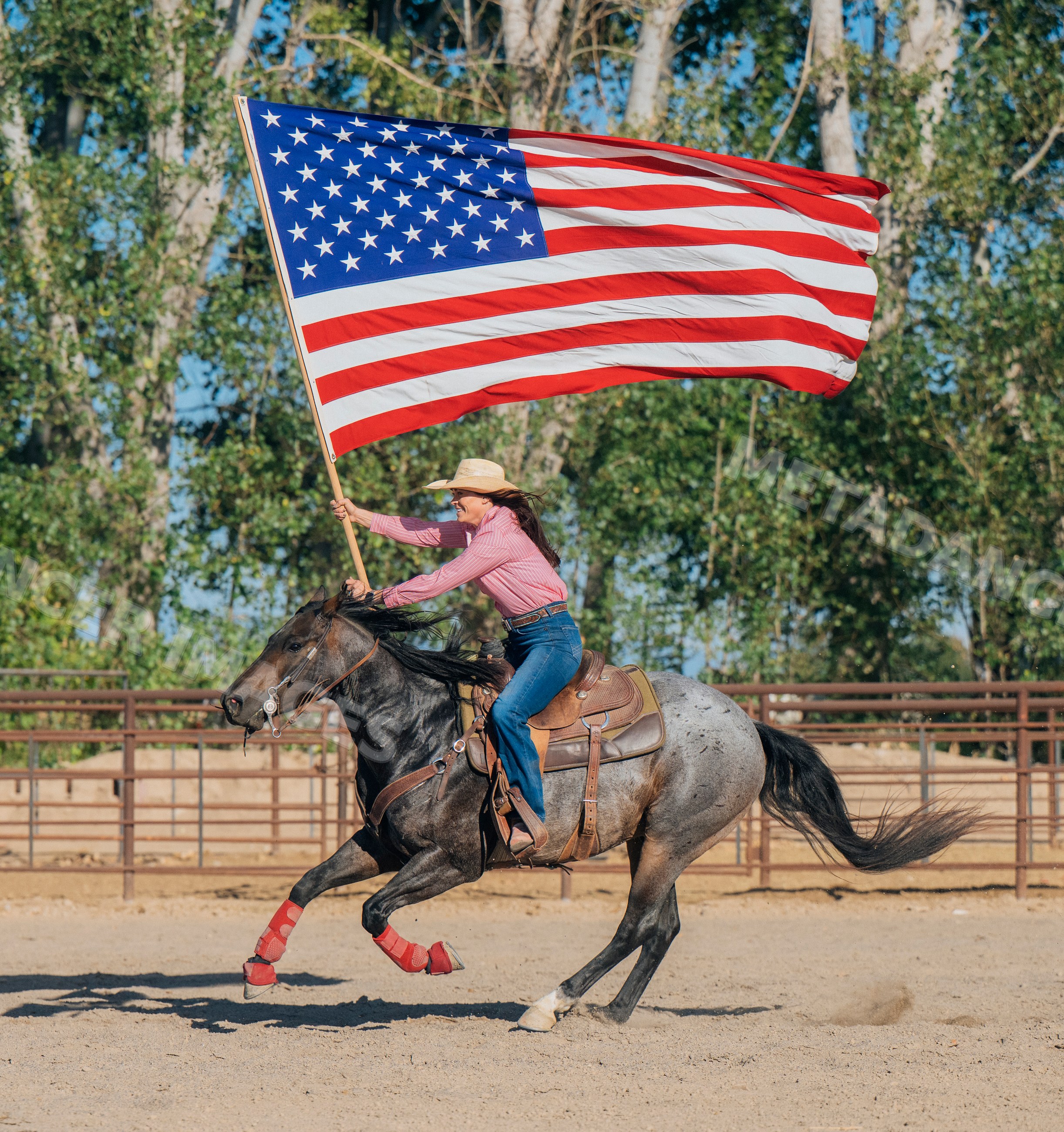 White woman riding horse holding american flag in western arena