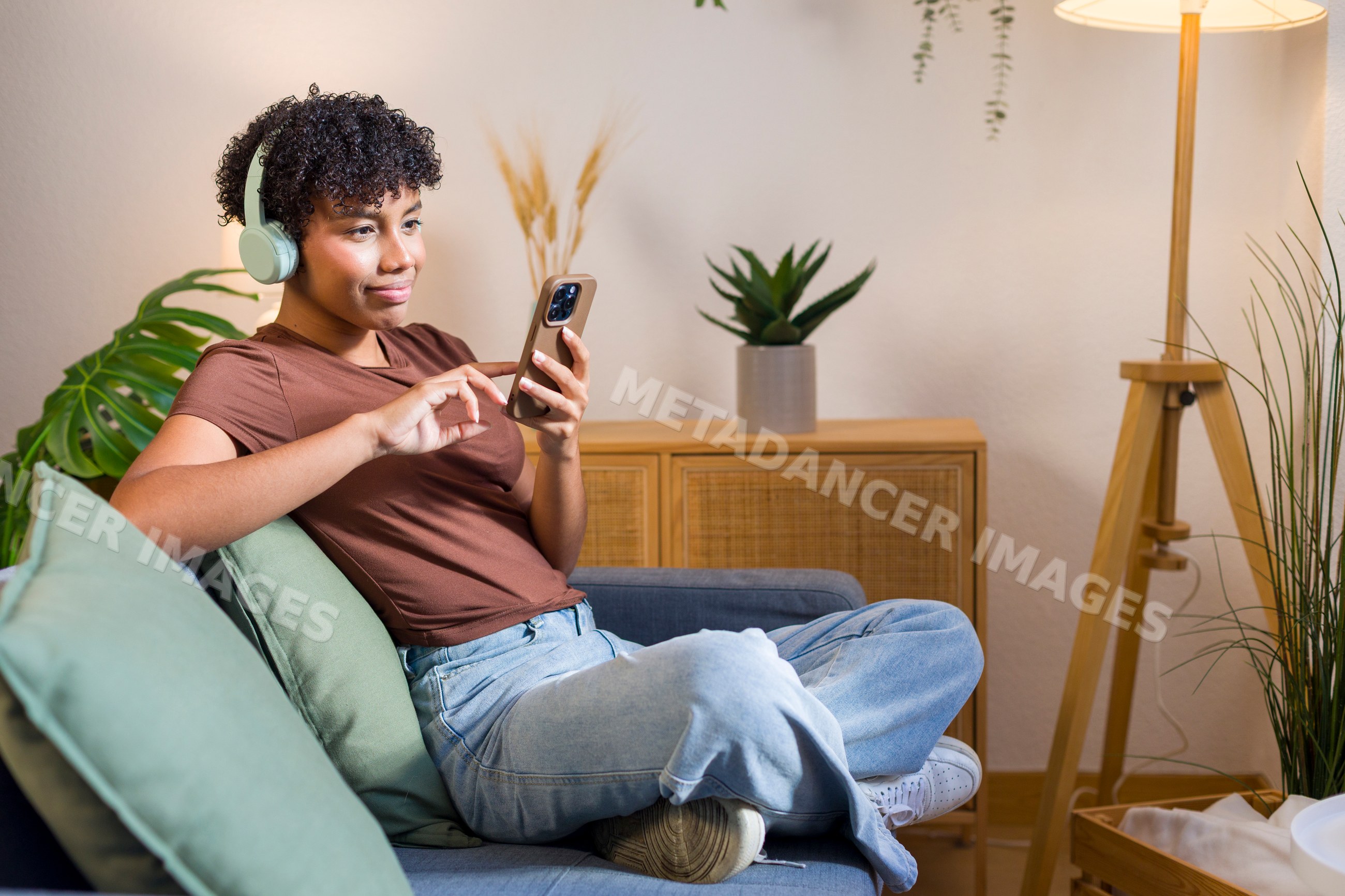 Young African American woman listening to wireless headphones using