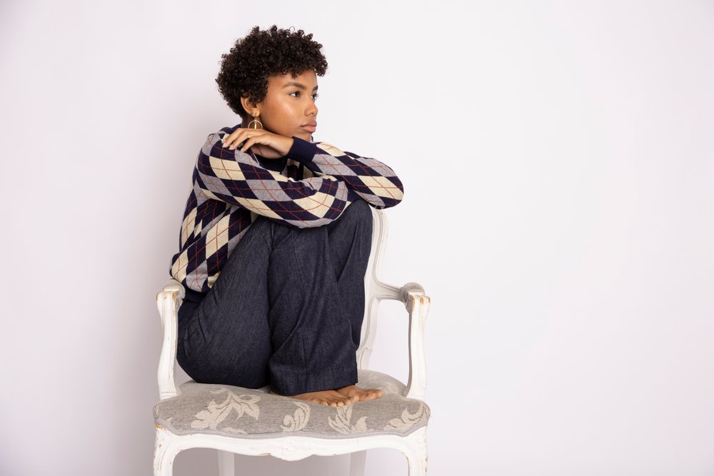 Hispanic woman sitting contemplatively on vintage chair