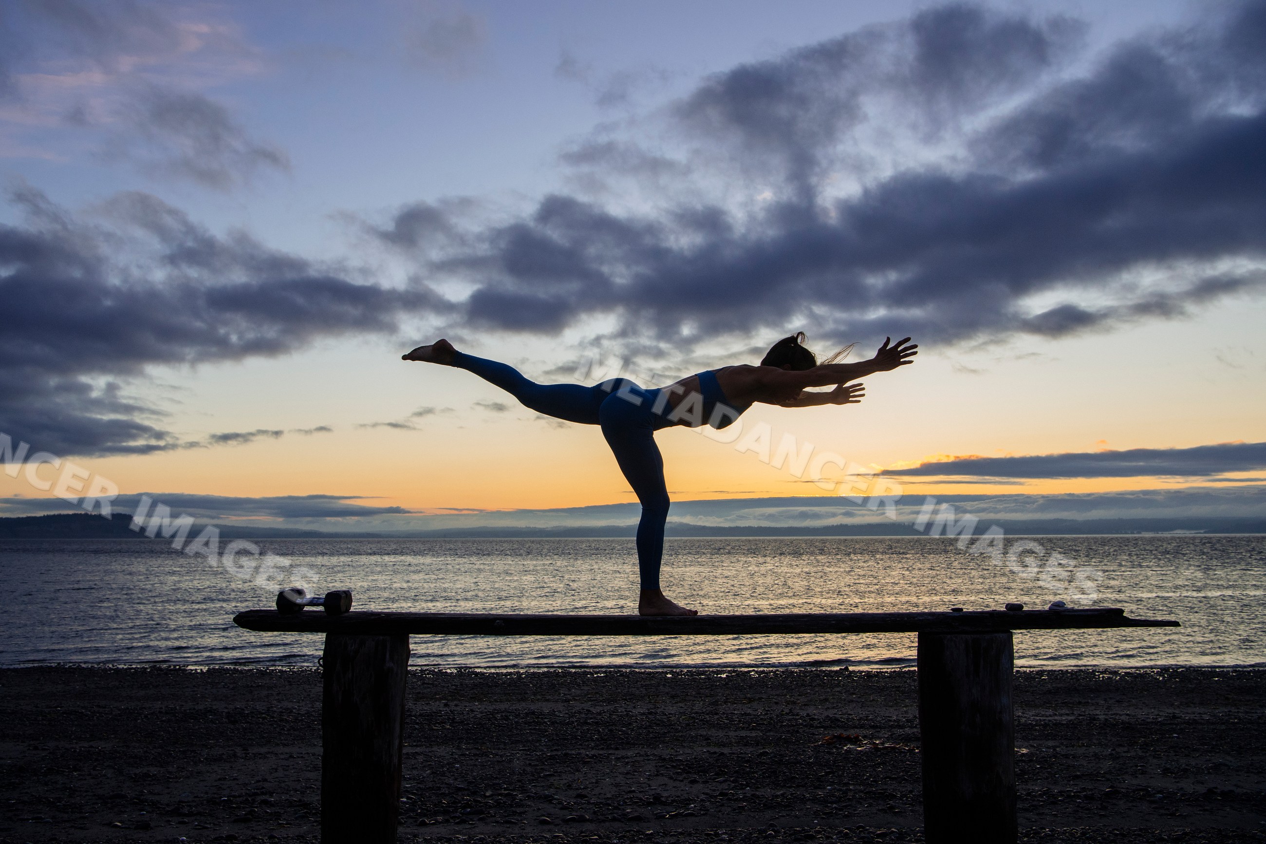 White person balancing in warrior iii yoga pose on beach bench