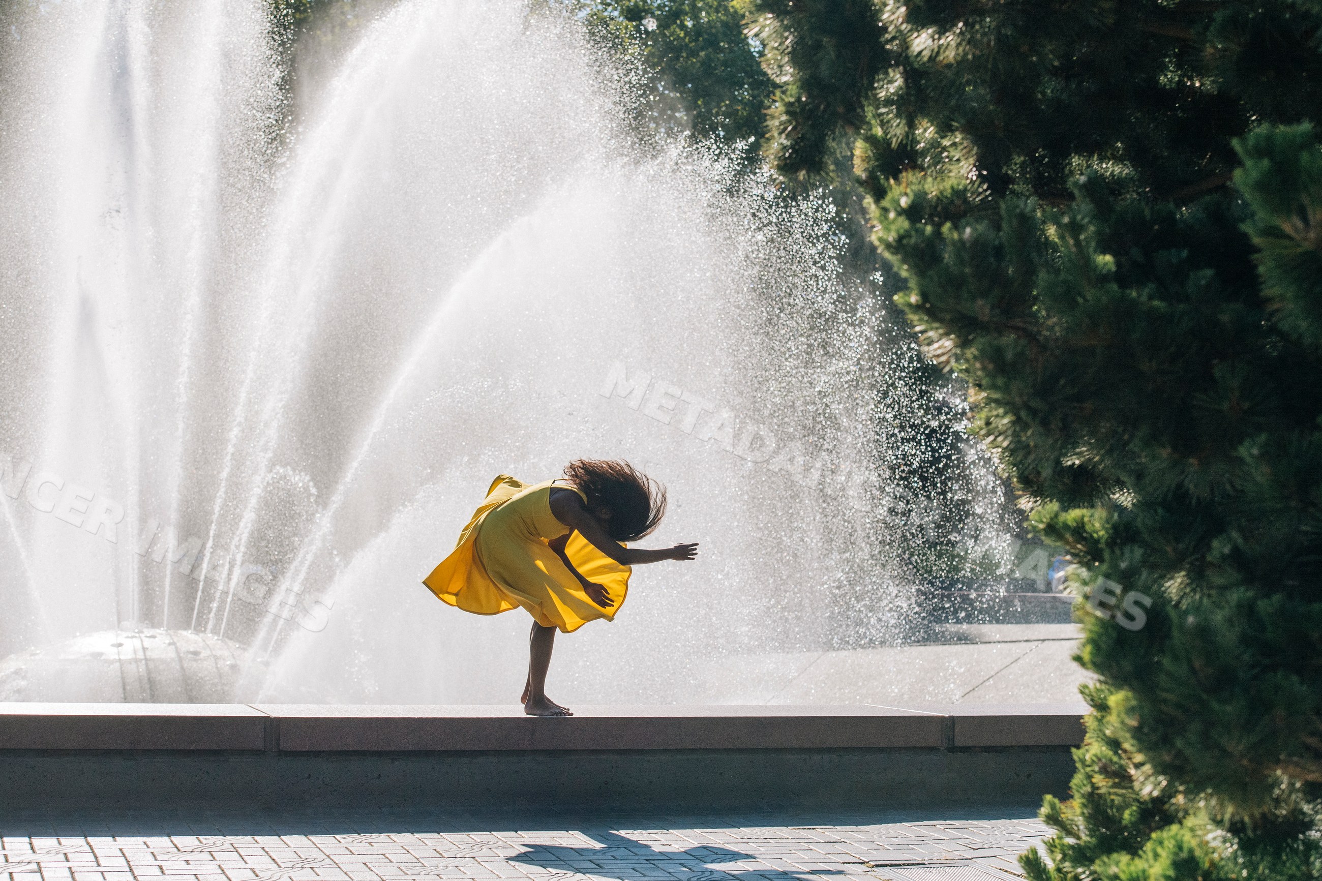 South Asian woman dancing barefoot by fountain