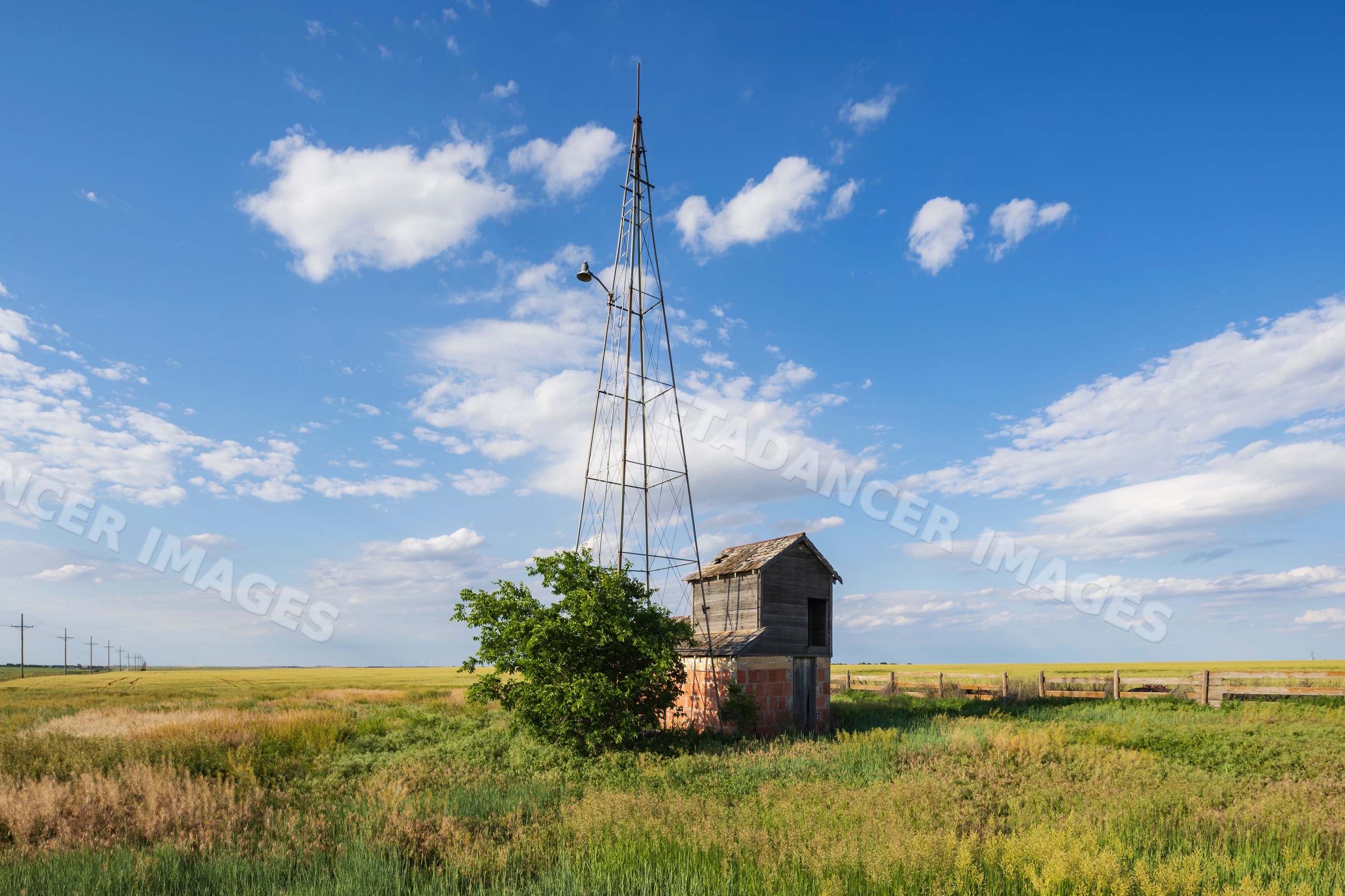 Old Windmill and Pumphouse in grassy kansas field with blue sky