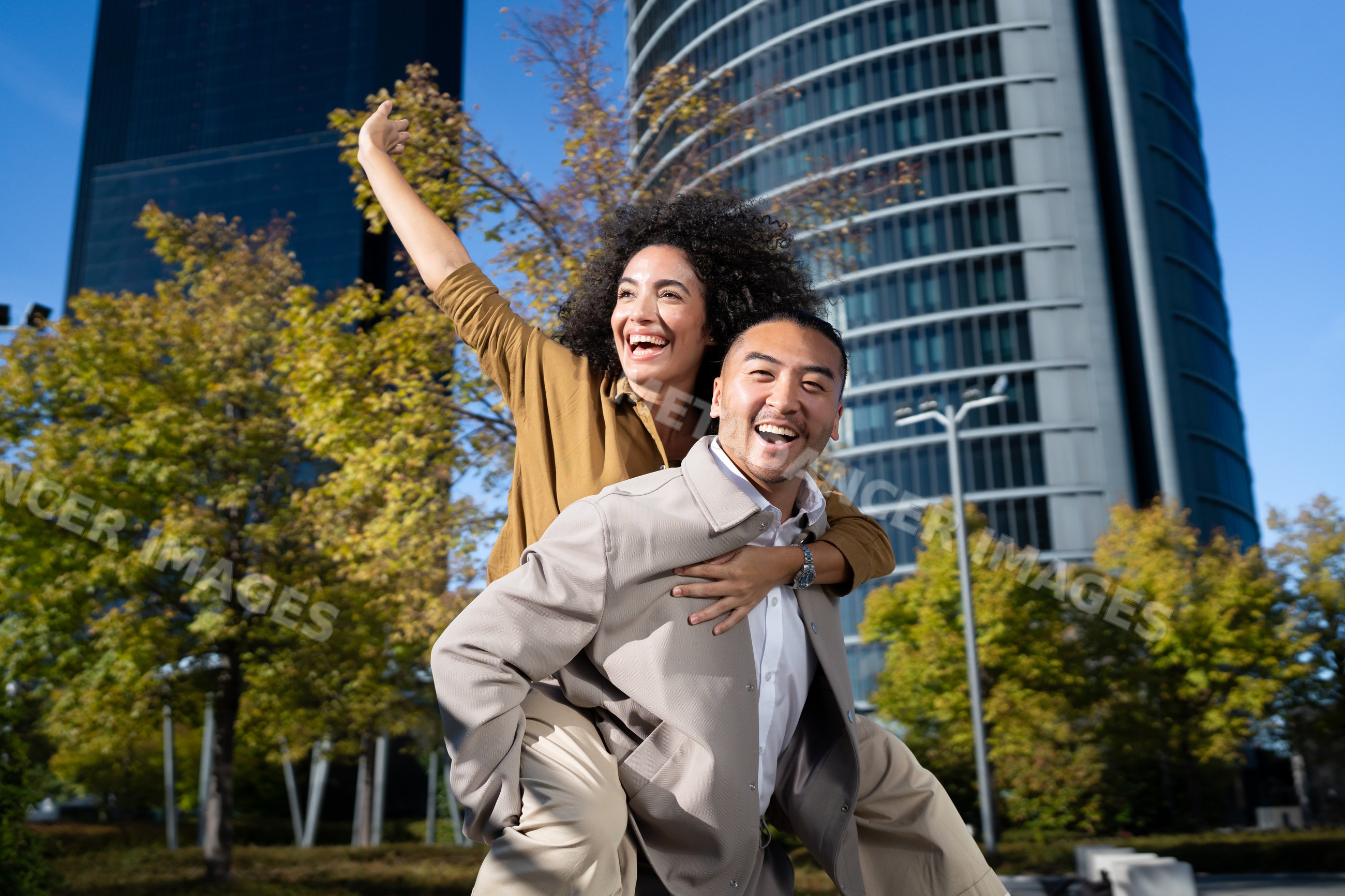 Couple enjoying piggyback ride in urban park with skyscrapers