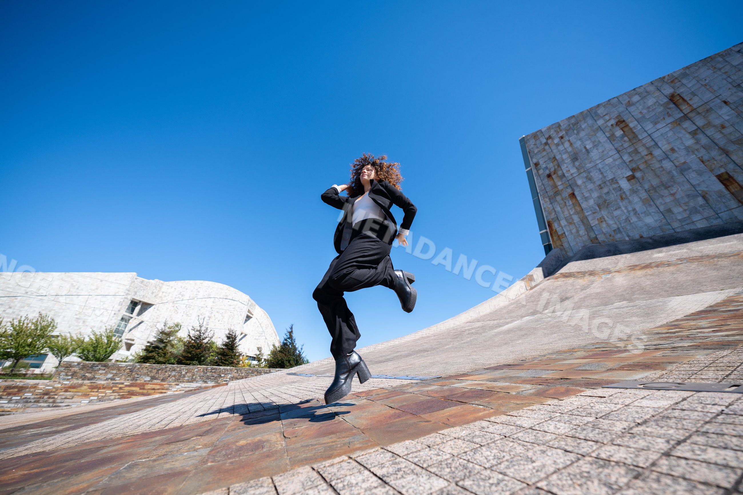 Businesswoman jumping outdoors by modern architecture