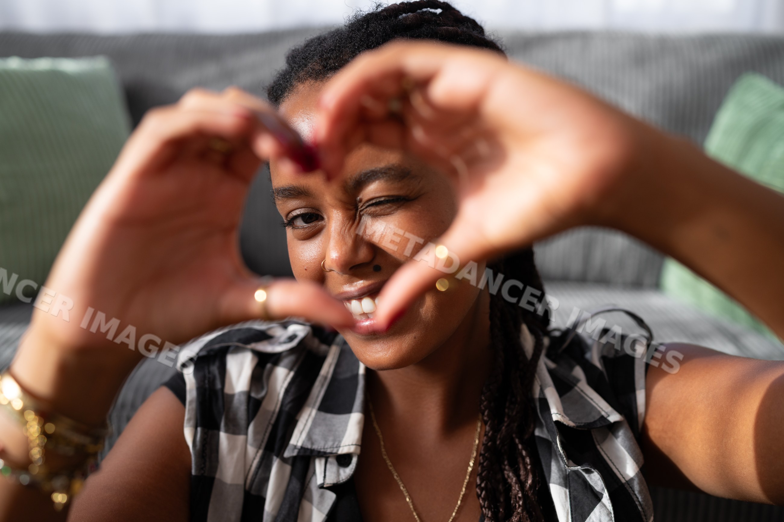 A young African American woman makes a heart shape with her hands