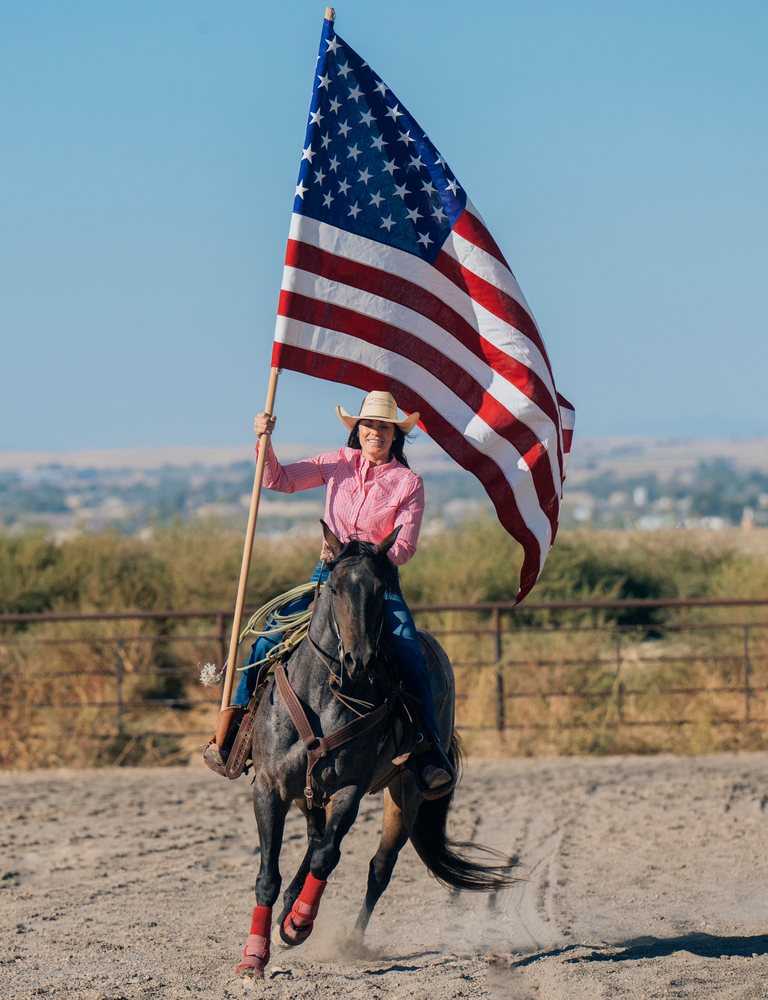 White woman horseback riding with american flag