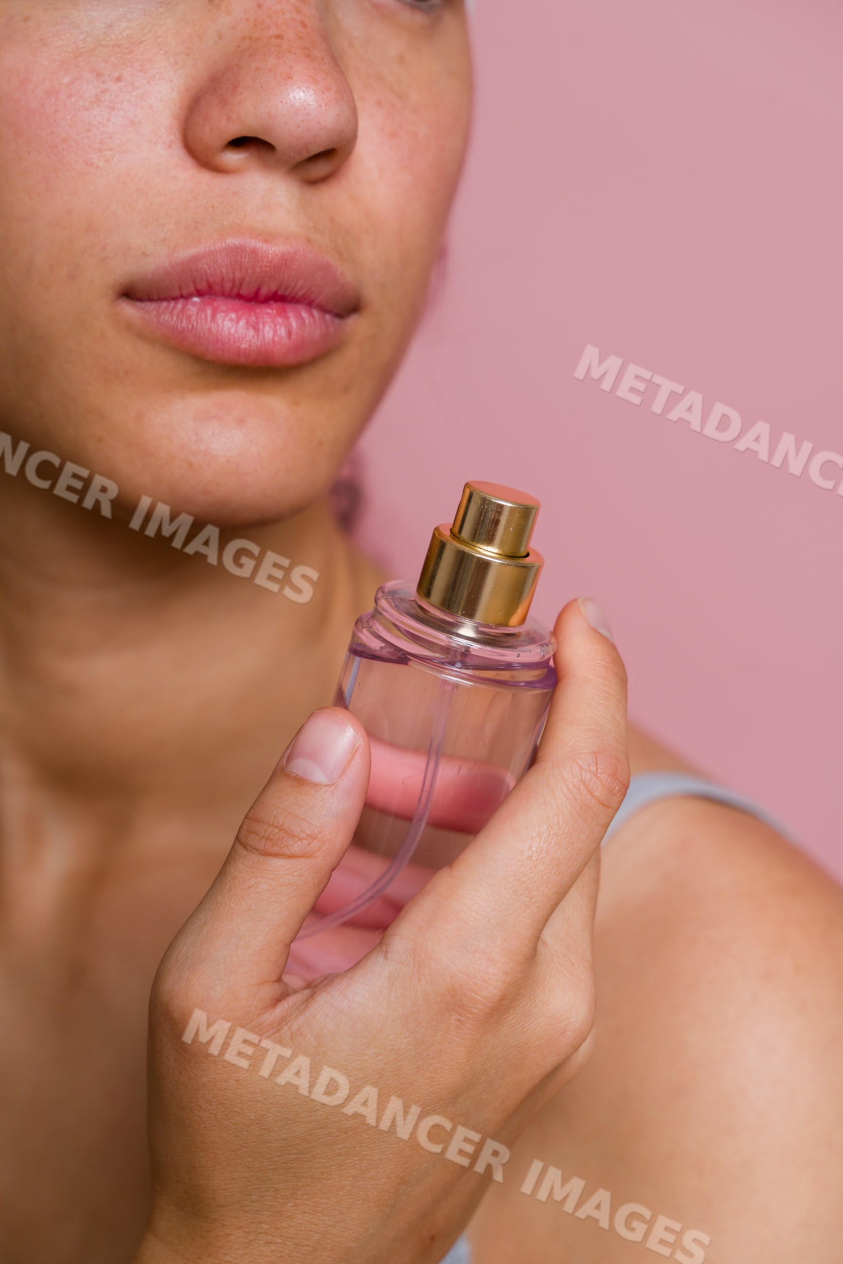 Hispanic woman holding perfume bottle with pink background