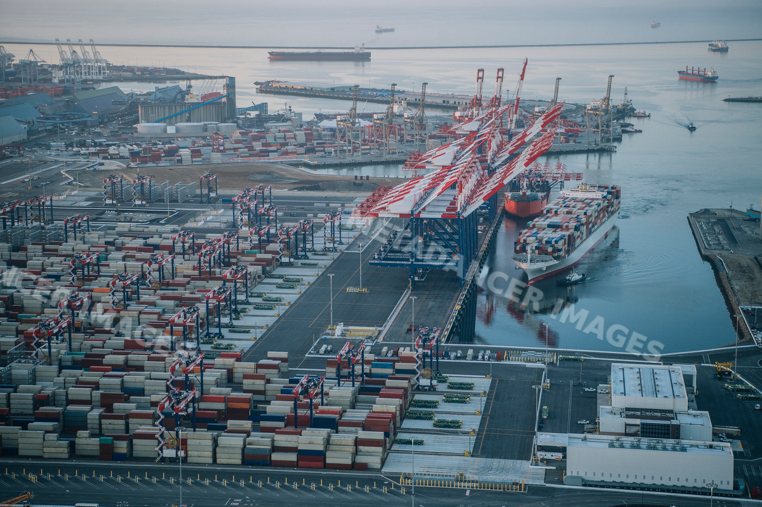 A container ship docked at a busy port with cranes and cargo