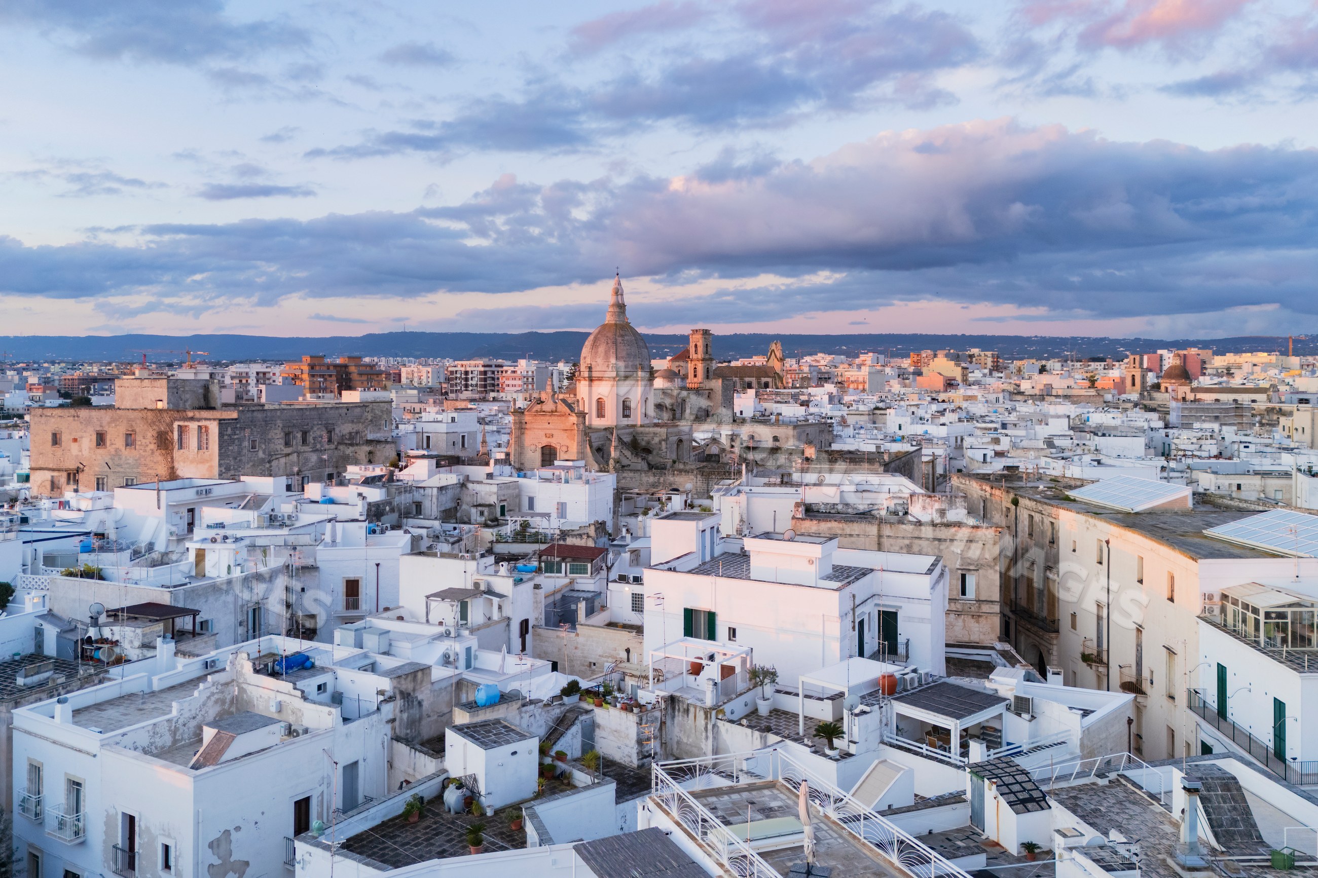 City rooftops with church dome at sunrise in monopoli, Puglia, Italy