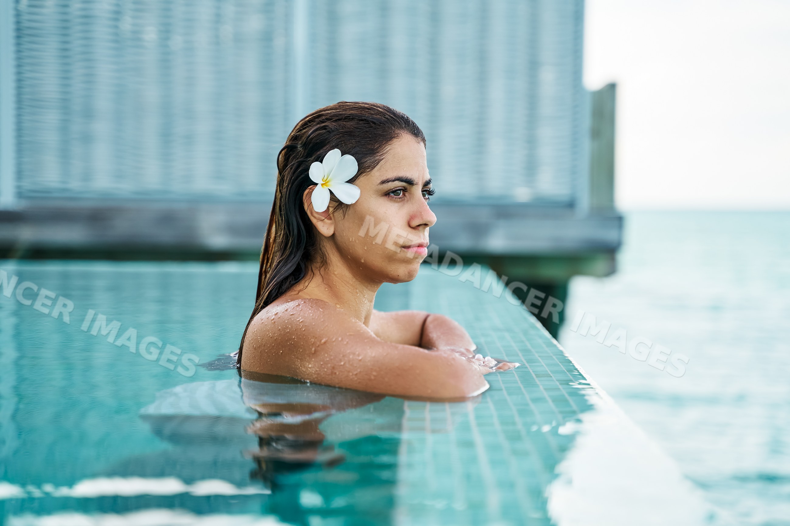 A white woman relaxing in a swimming pool with a flower in her hair