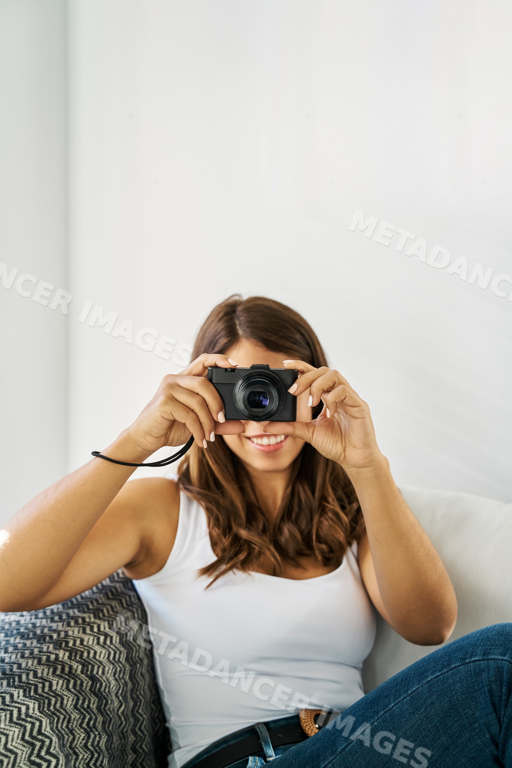 A young white woman takes a photo with a digital camera indoors