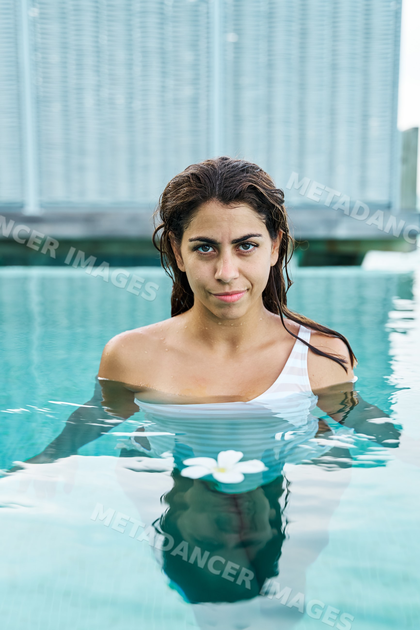 A white woman enjoys a tranquil swim with a flower in a pool