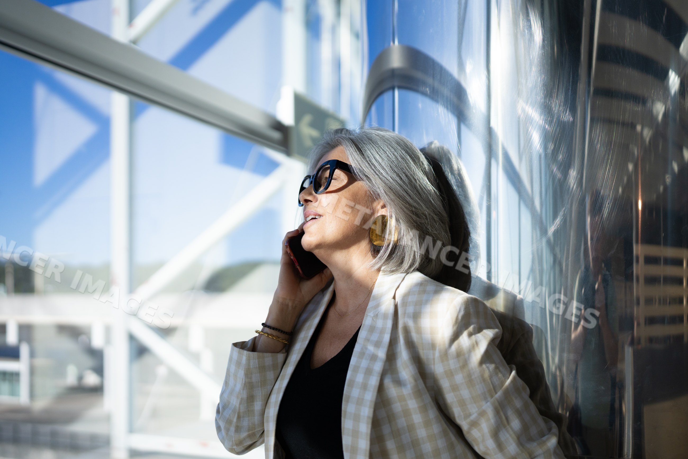 Businesswoman with gray hair making phone call in modern building