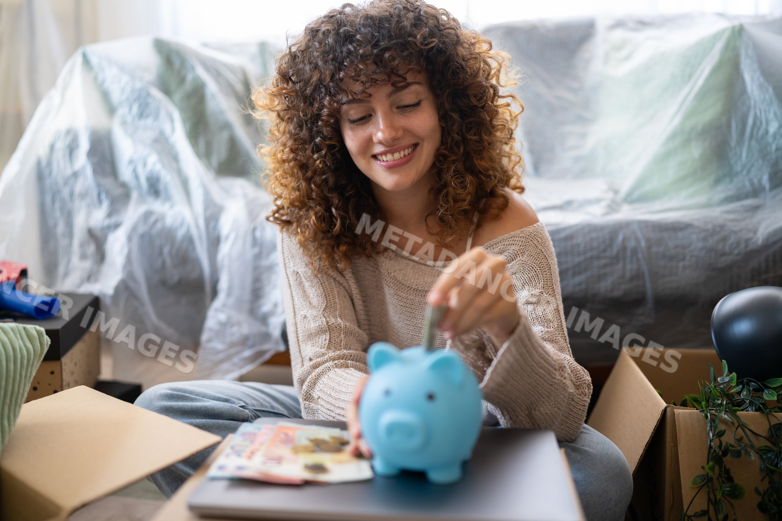 White woman saving money by inserting coin into piggy bank at home