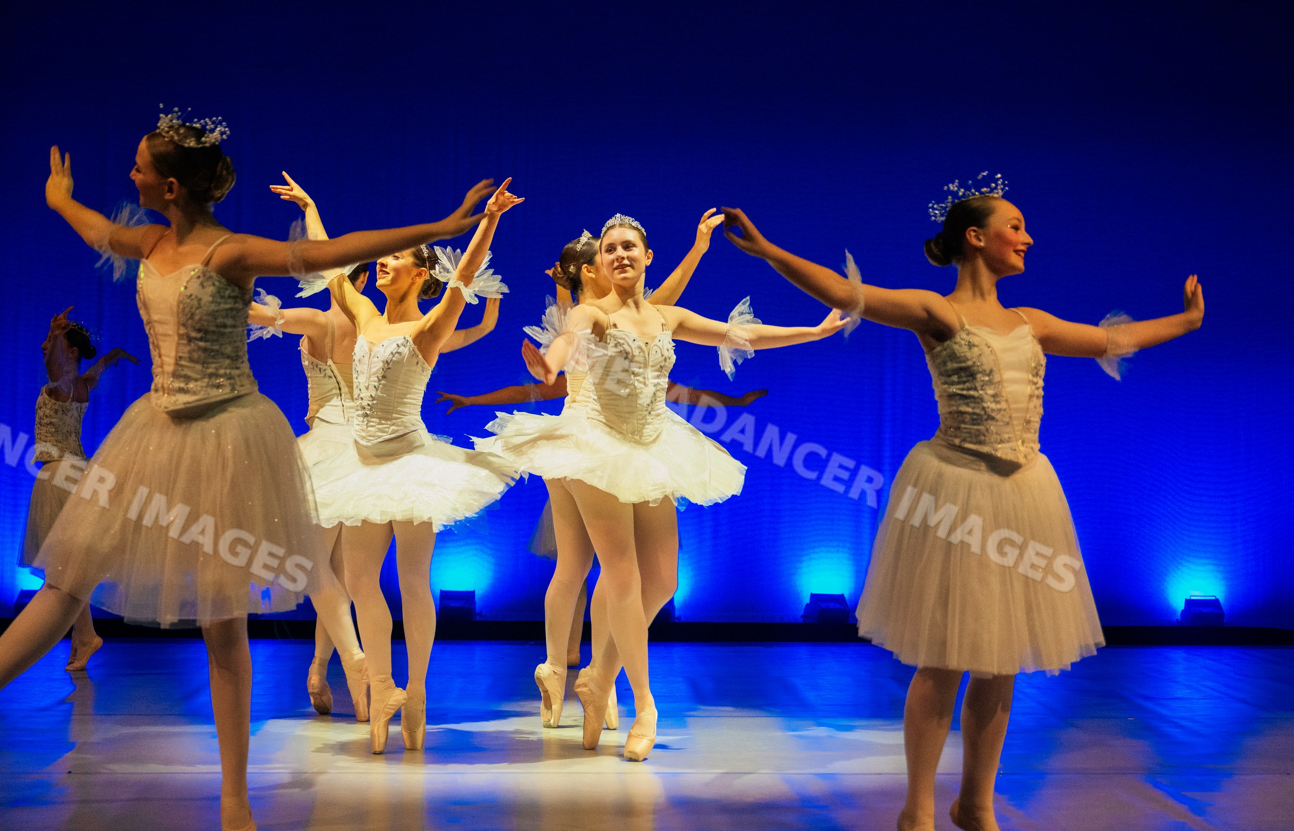 Ballerinas perform a holiday ballet in elegant white tutus on stage