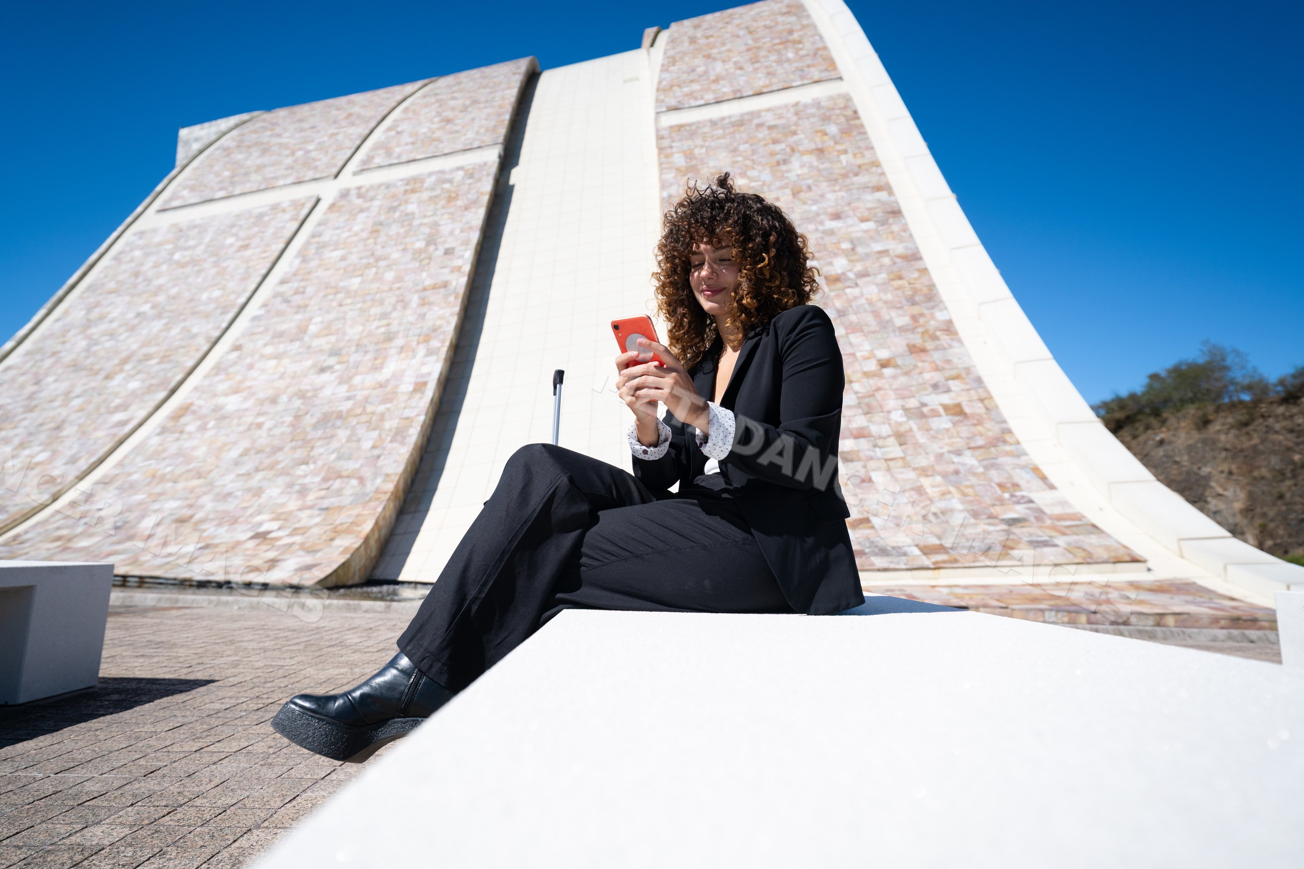 Businesswoman using smartphone sitting outdoors