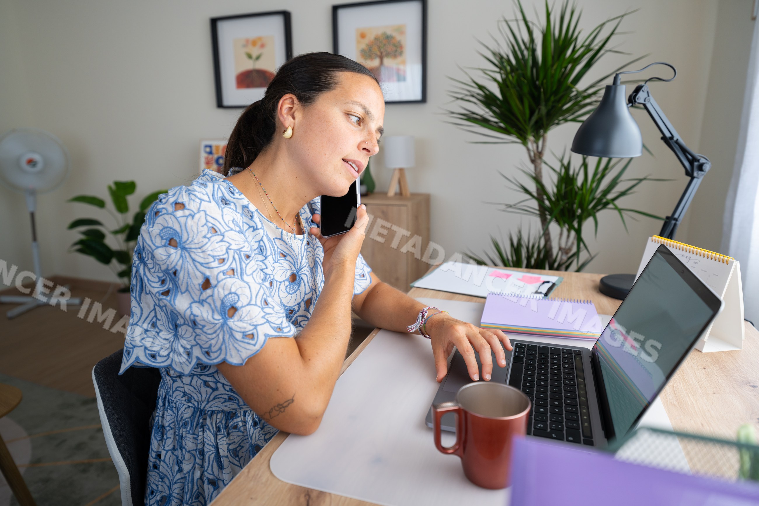 White woman telecommuting at home office desk with laptop and phone