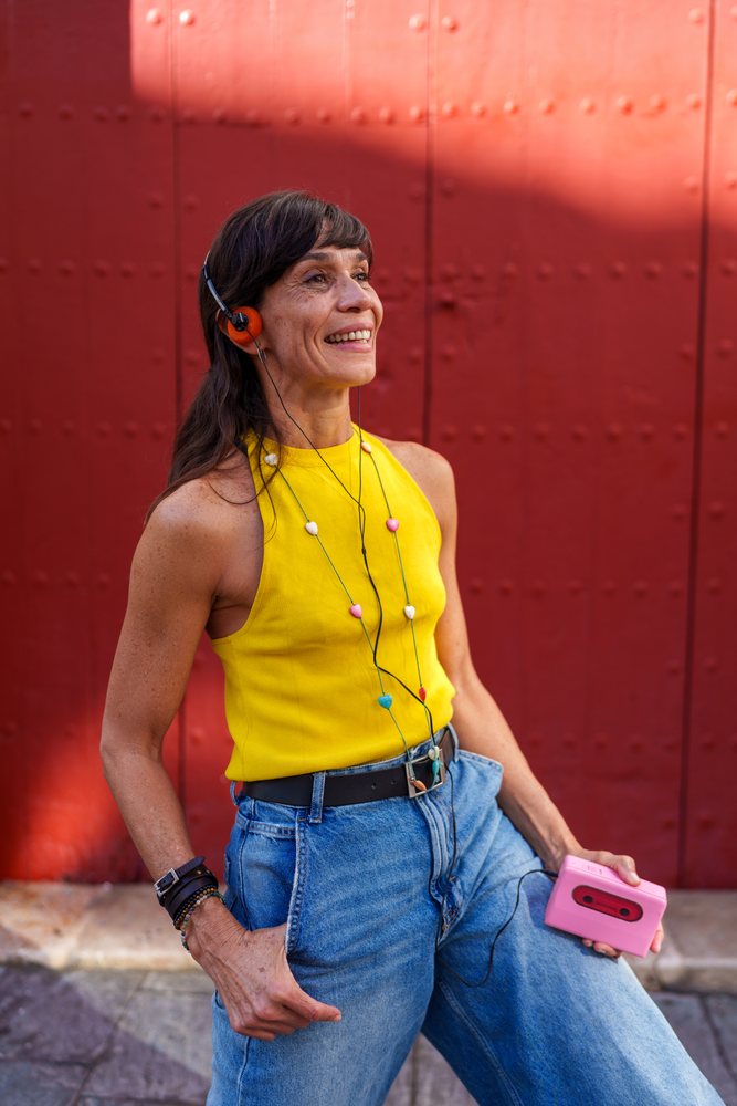 Hispanic woman enjoying music with a pink cassette player outdoors