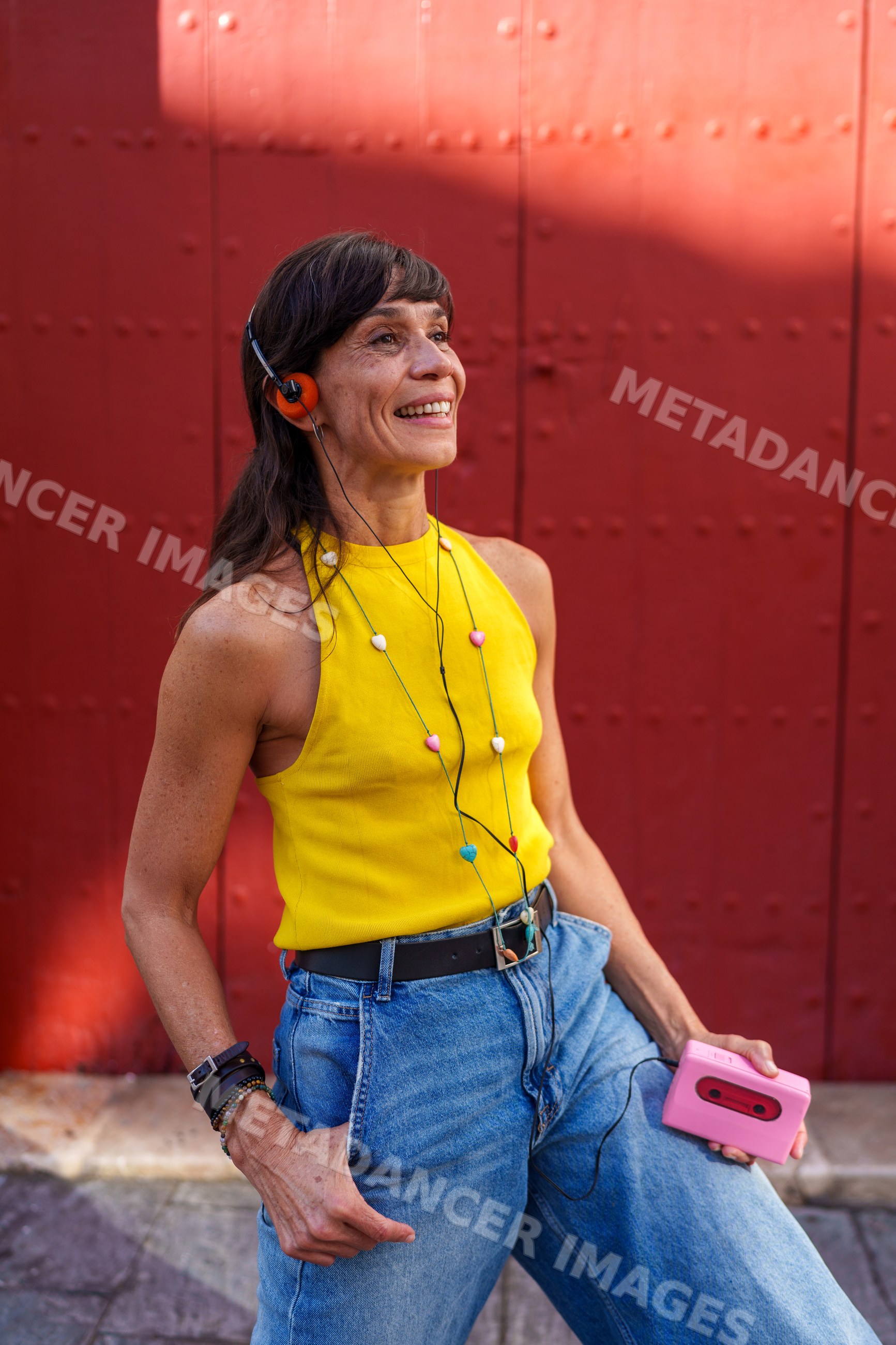 Hispanic woman enjoying music with a pink cassette player outdoors