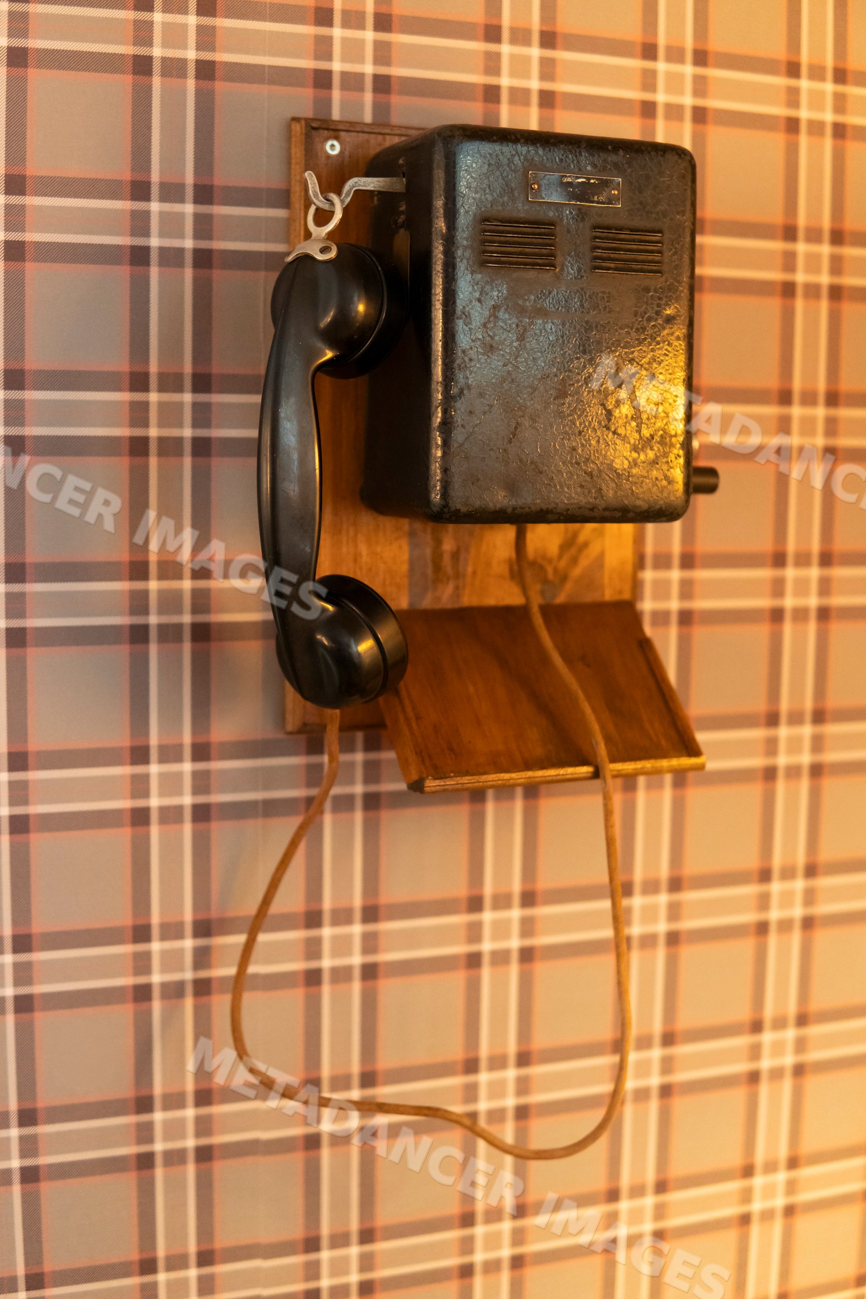 Retro black wall telephone with corded handset mounted on wood