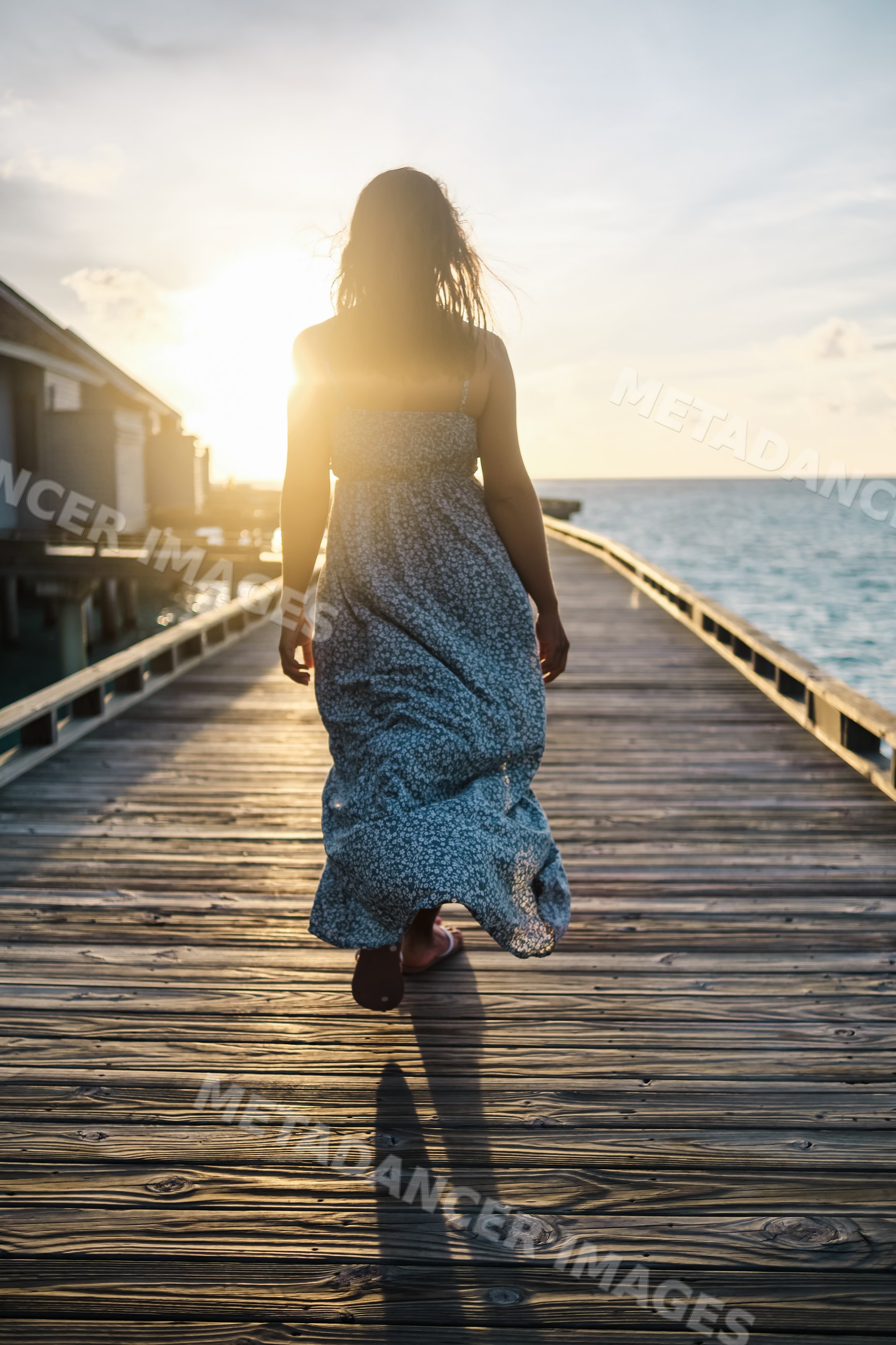 A white woman walks on a wooden pier over the ocean