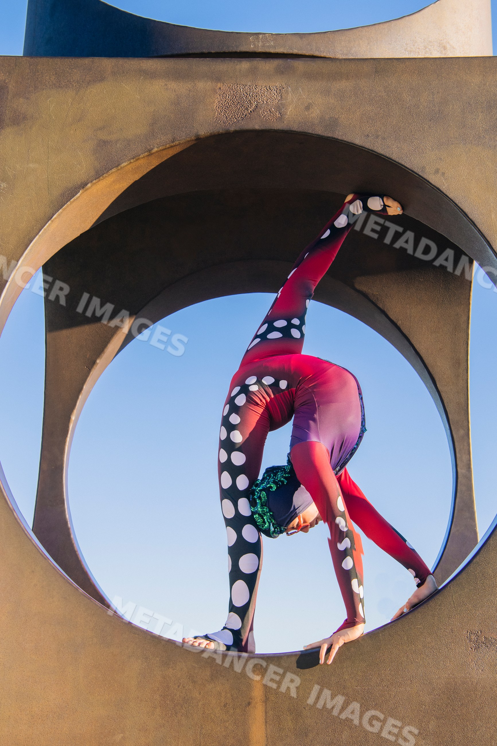Contortionist in red polka dot costume balancing in circular arch
