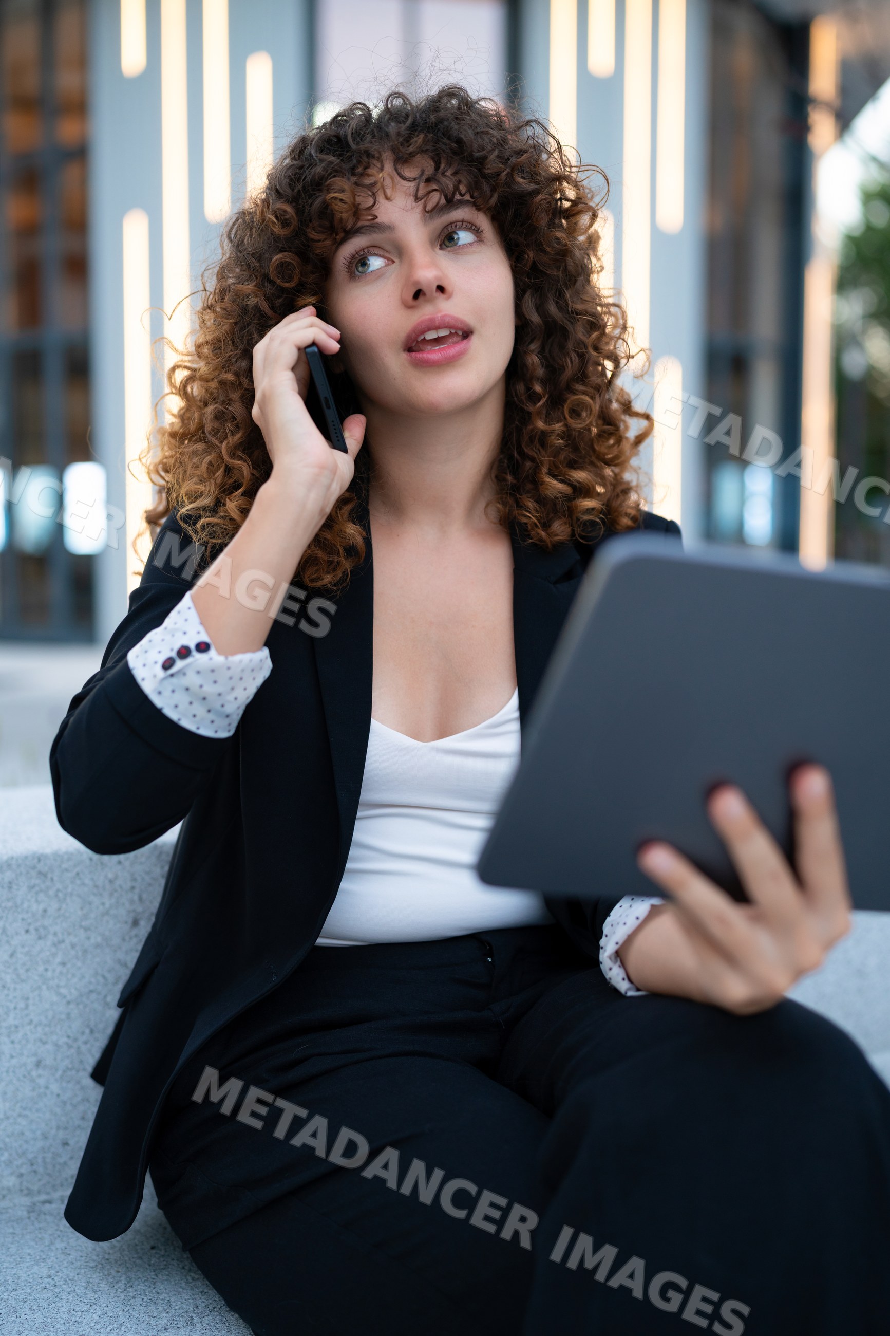 Young white woman using phone and tablet outdoors