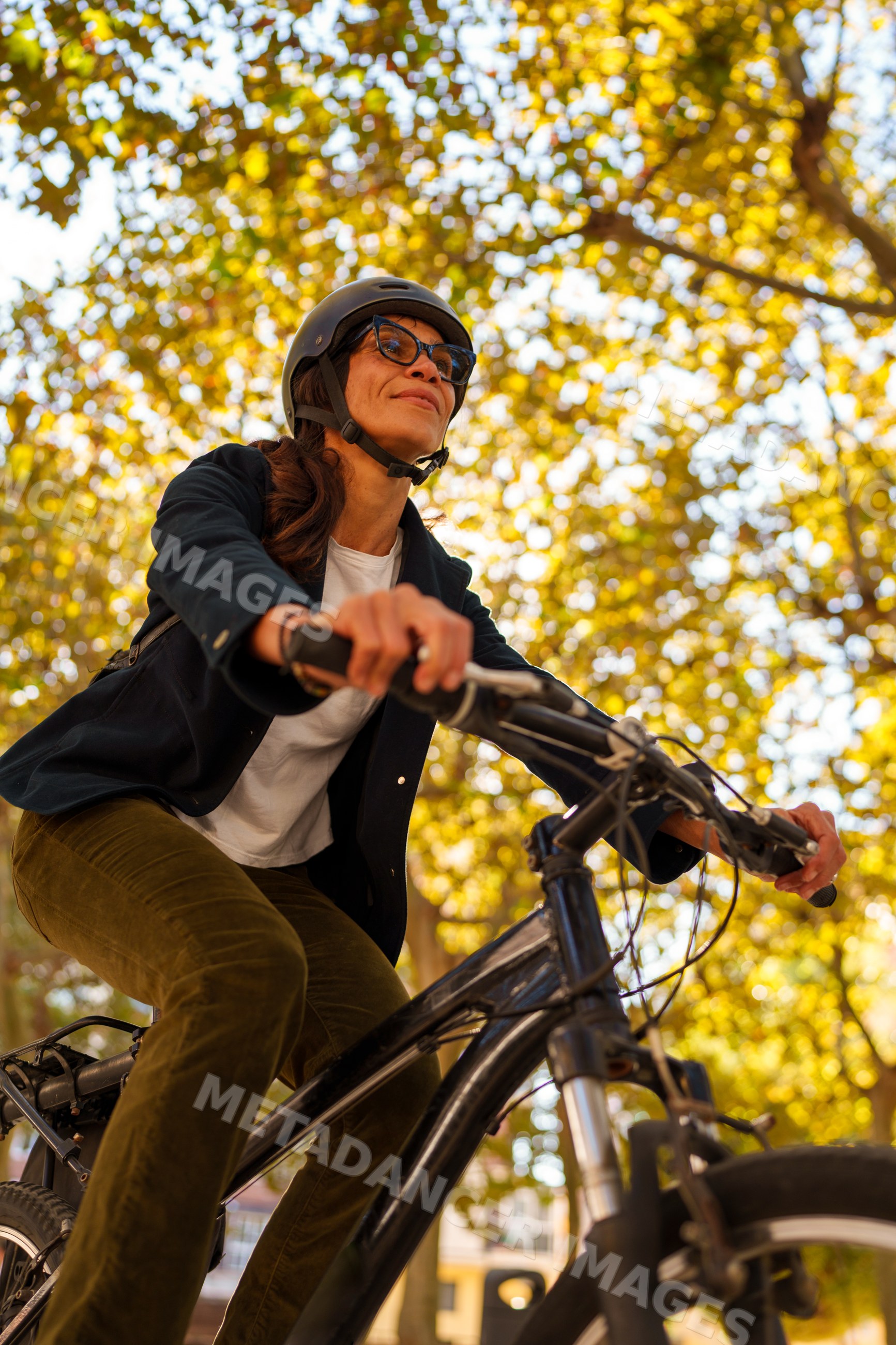 Hispanic woman riding bike outdoors under autumn trees in a park