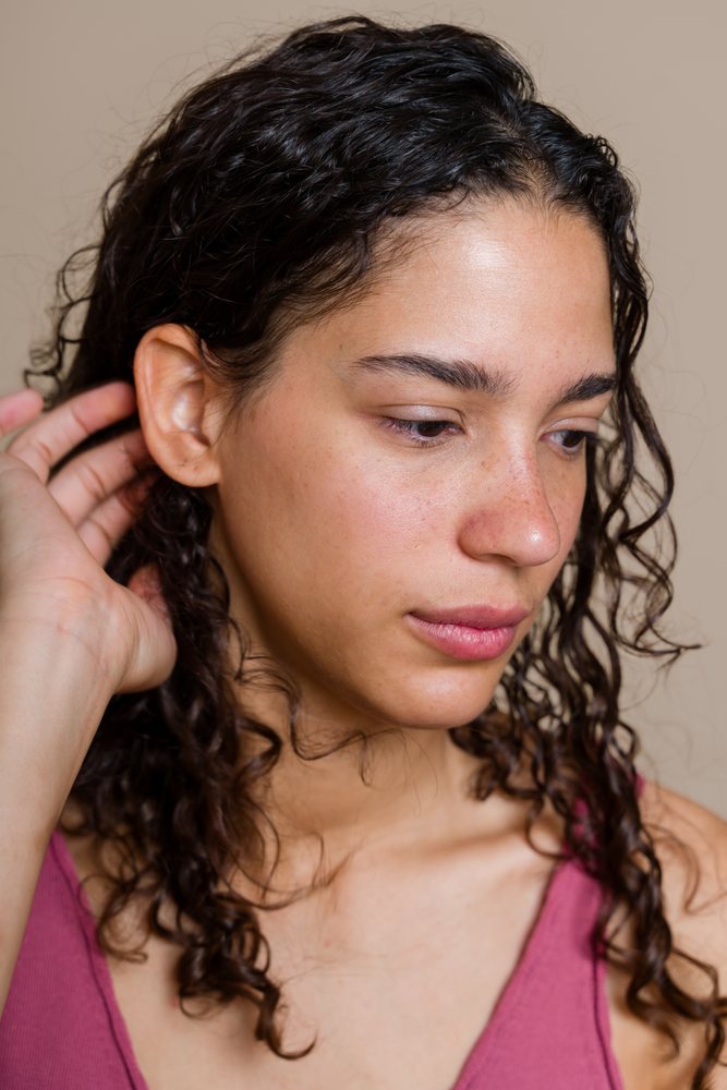 Hispanic woman with curly hair touching hair