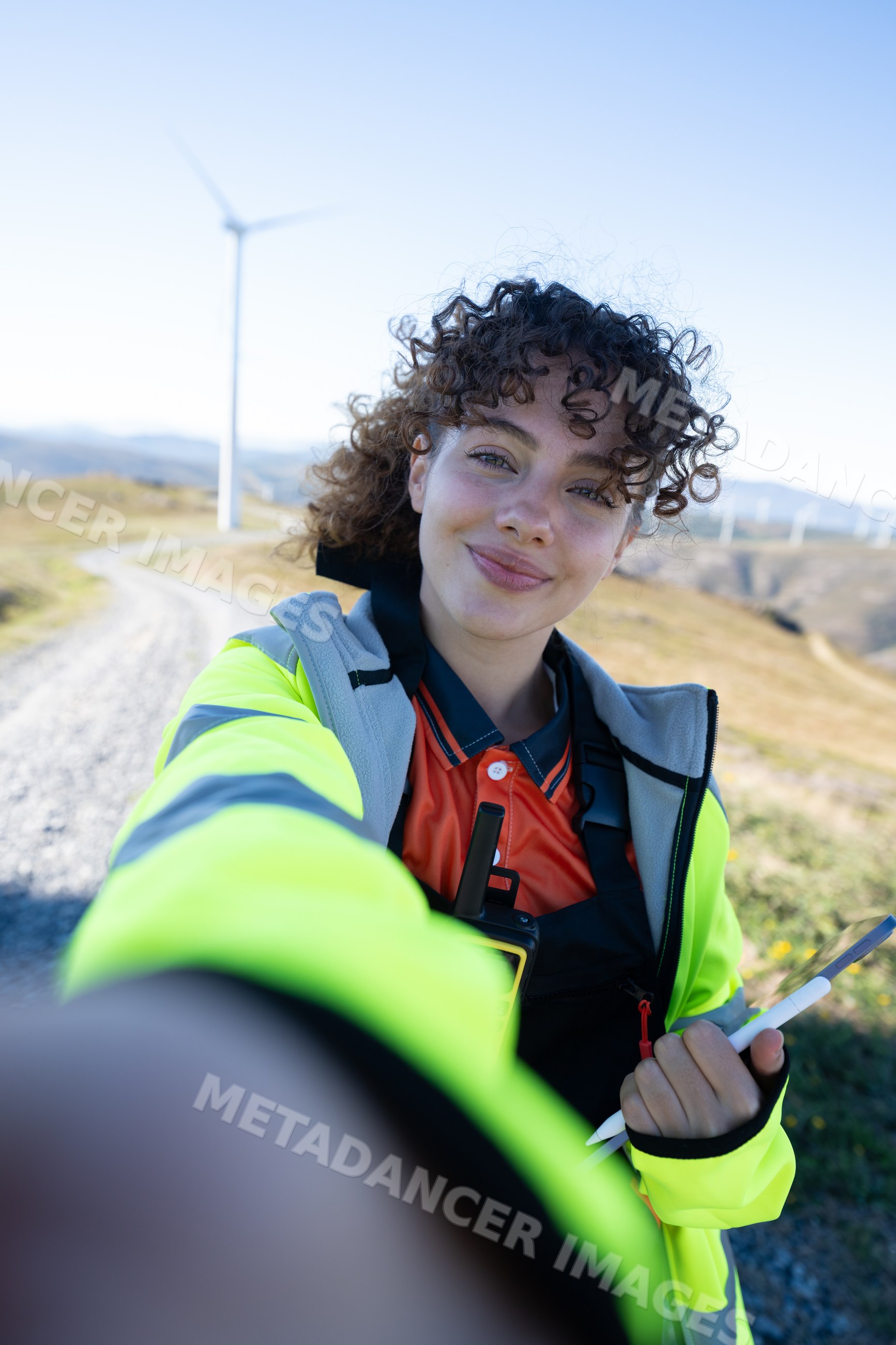 White woman taking selfie at wind farm in Galicia Spain wearing safety