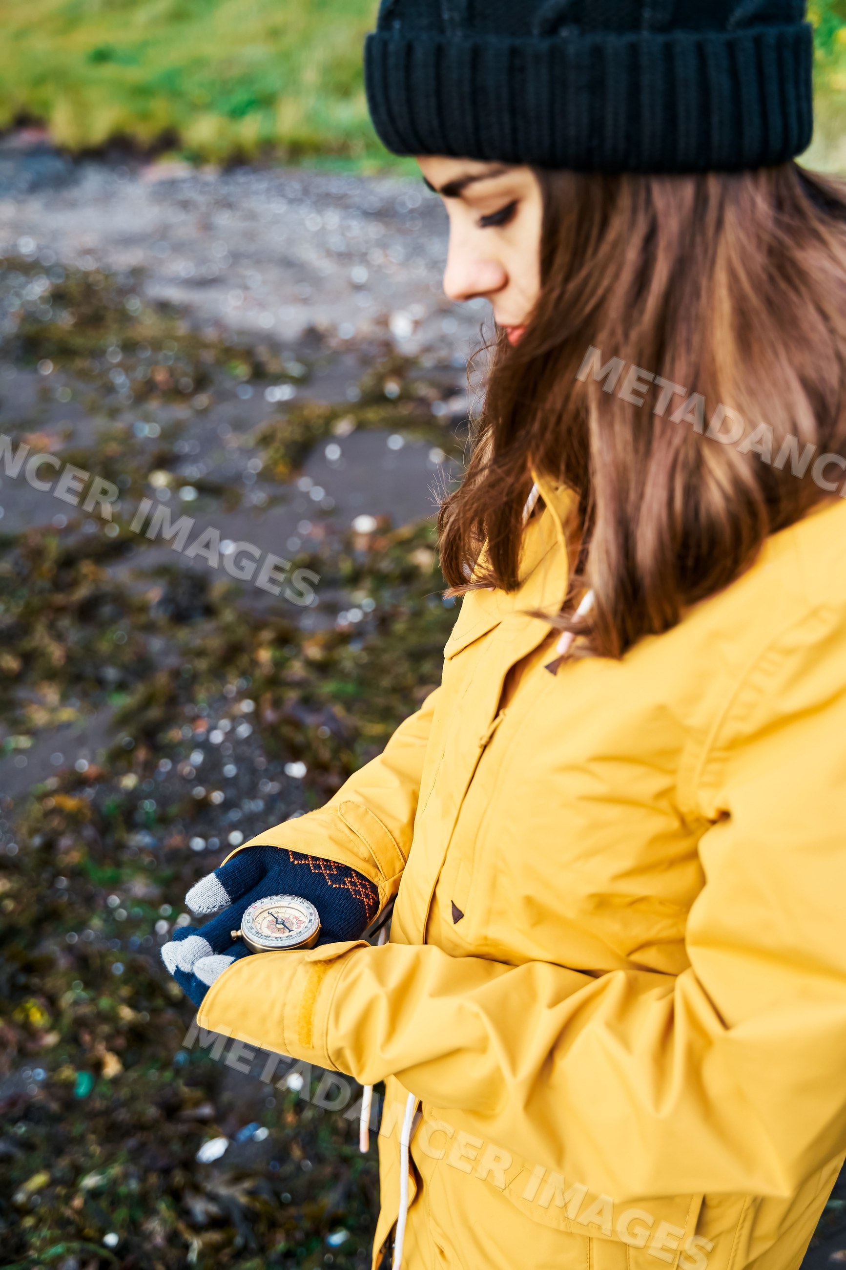 A white woman examines a compass while standing outdoors
