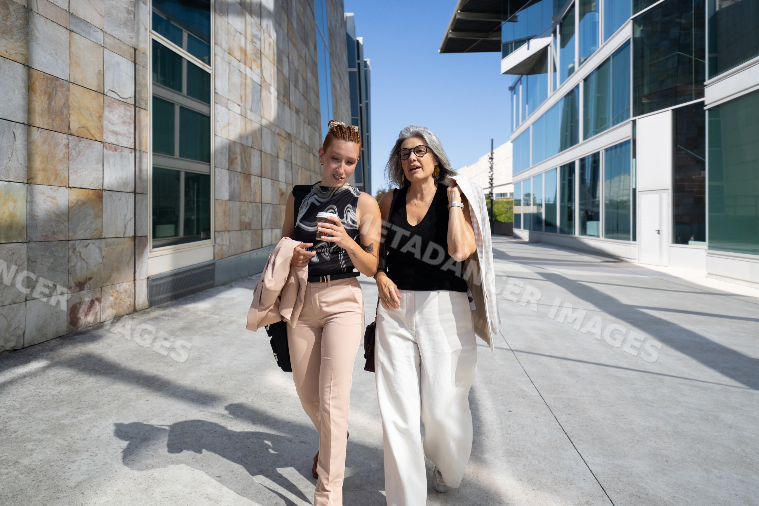 Businesswomen walking and talking outside modern buildings