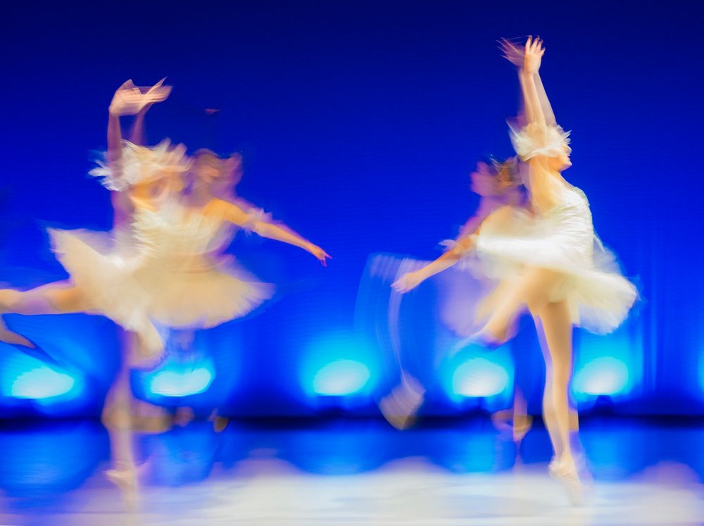 Blurred ballet dancers perform classical dance on stage with dramatic