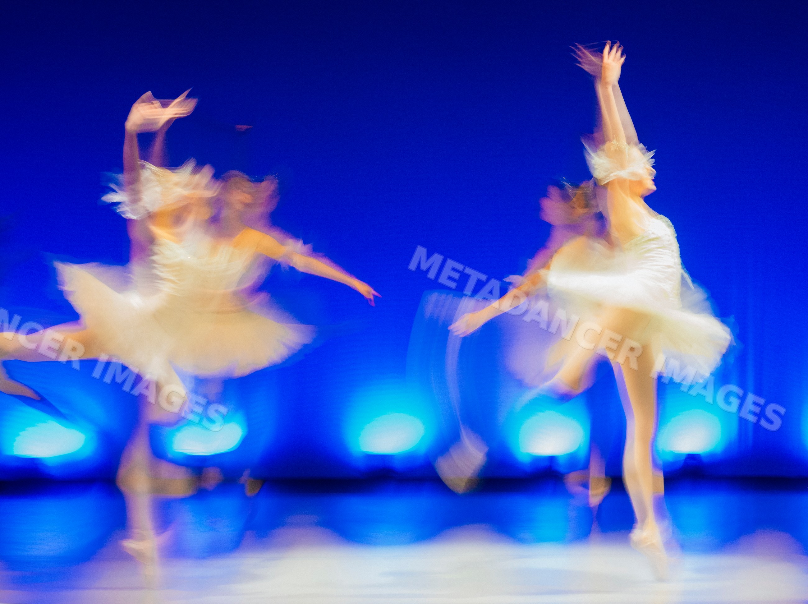 Blurred ballet dancers perform classical dance on stage with dramatic