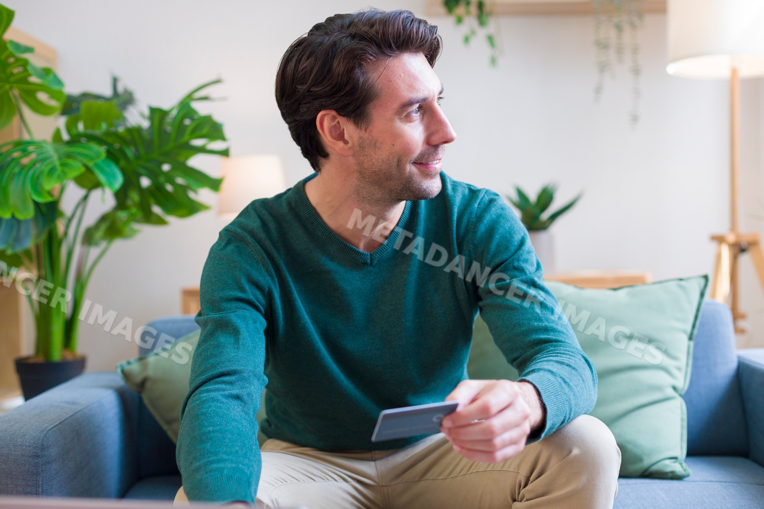White man sitting on sofa credit card in modern living room