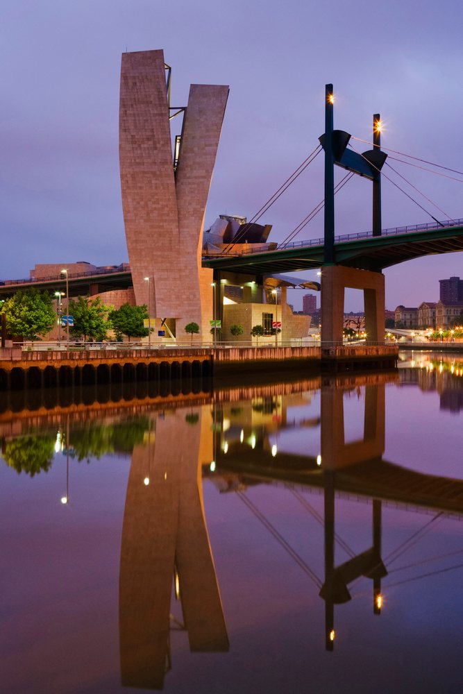 Guggenheim museum bilbao and bridge reflecting in the river at dusk