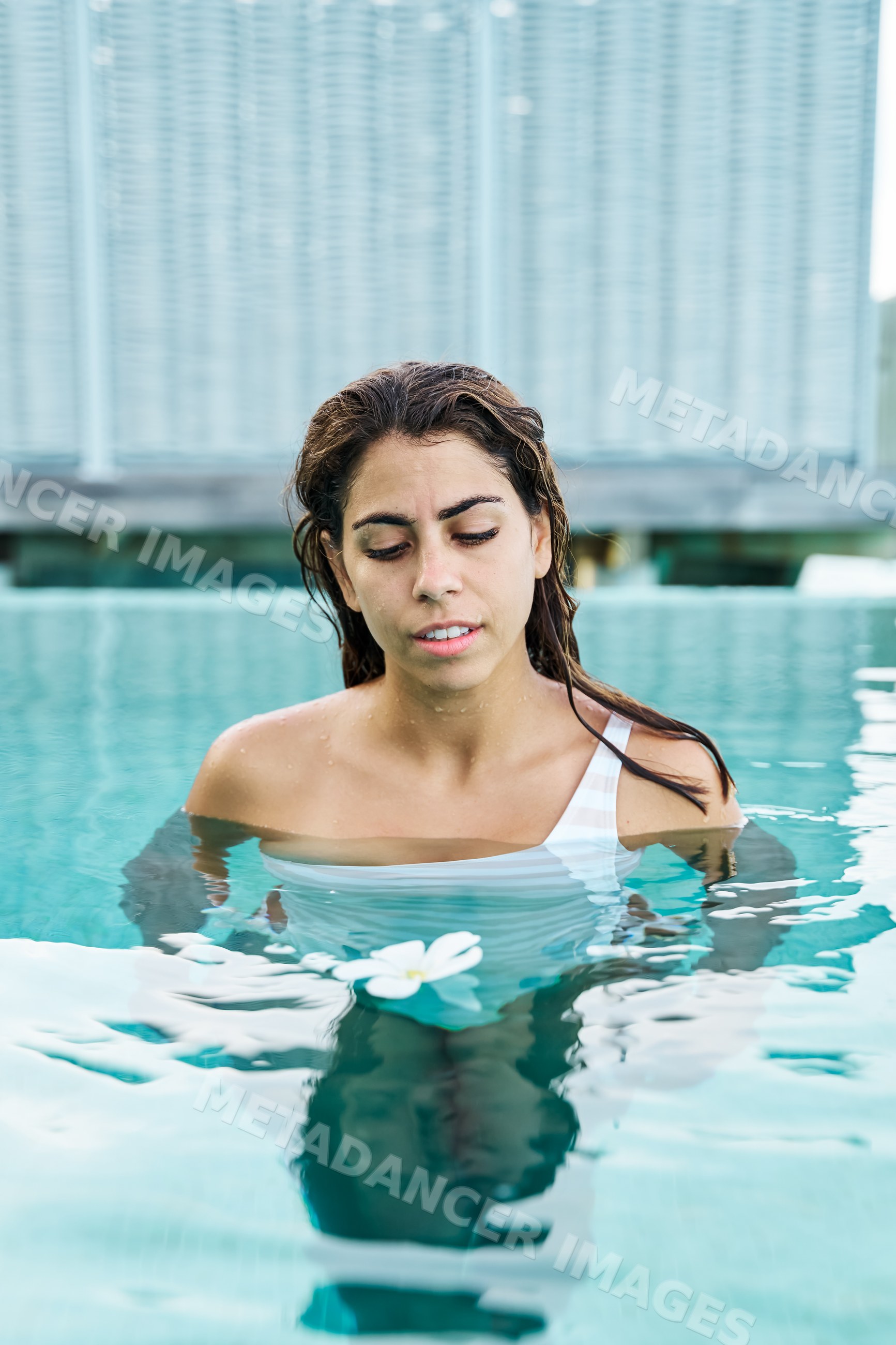 White Woman relaxing in a swimming pool with a floating flower