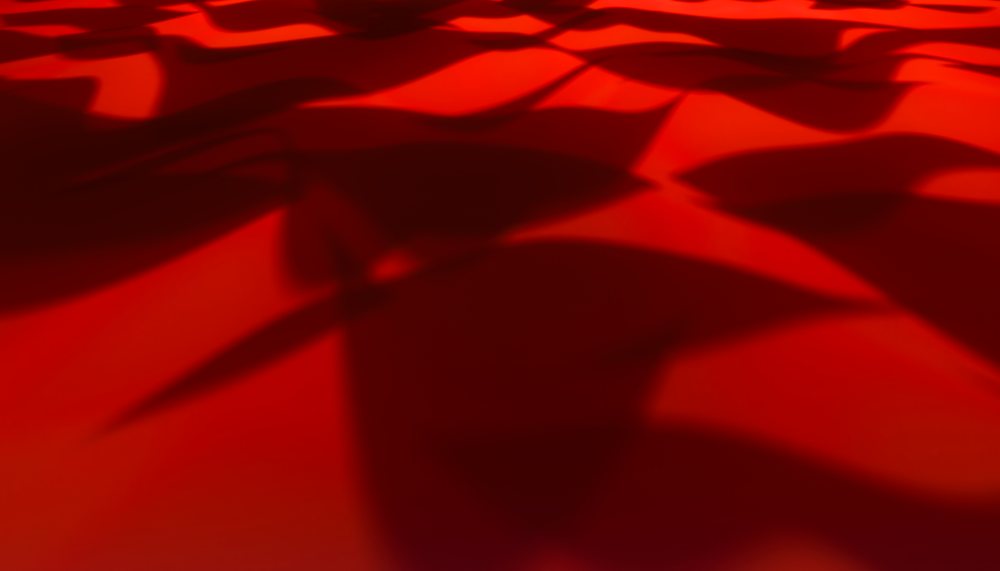 Red fabric with flowing folds and shadow patterns close-up