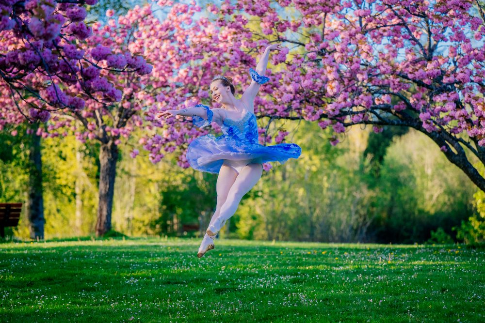 A ballerina in a blue costume leaps gracefully
