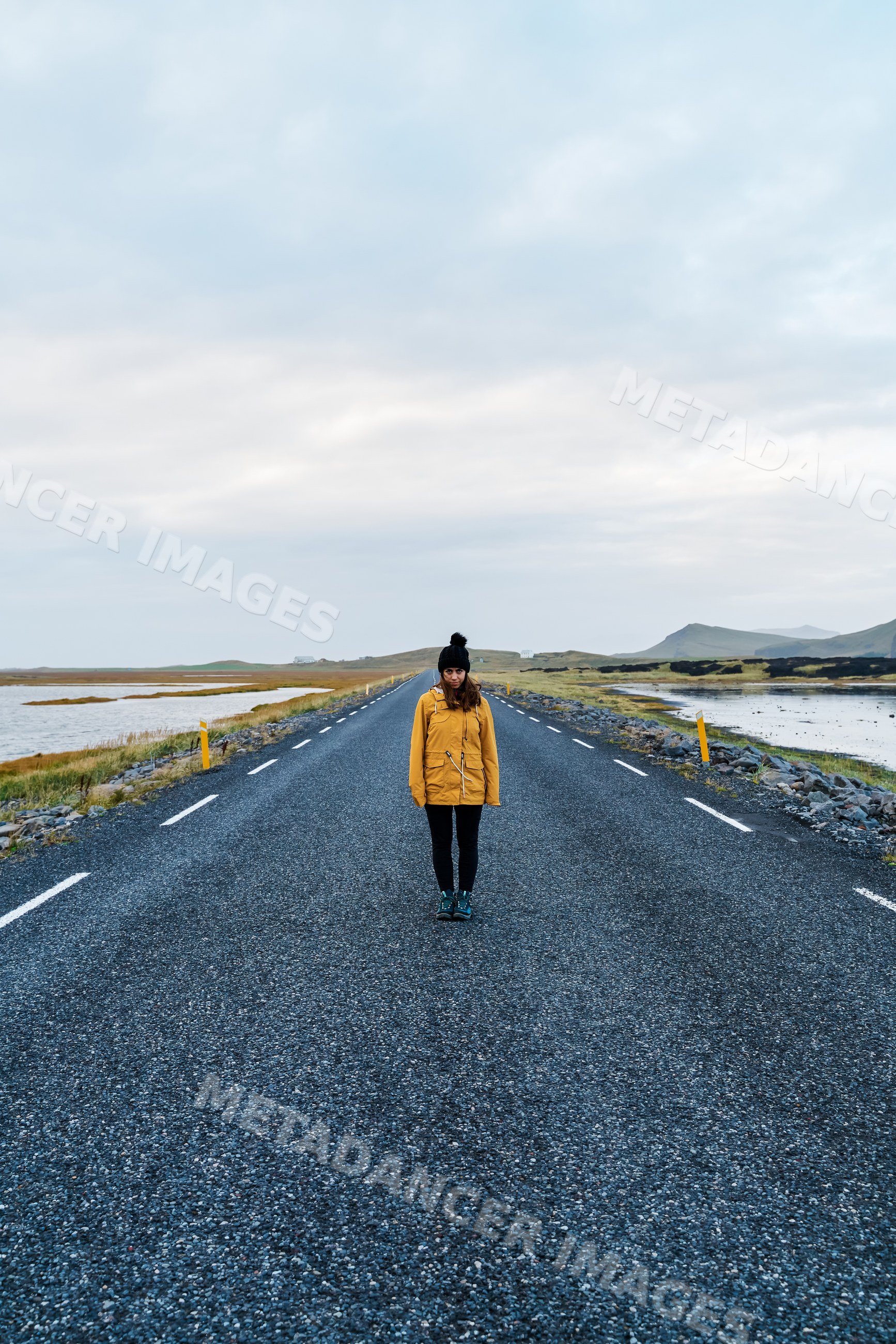A white woman stands alone on a paved road